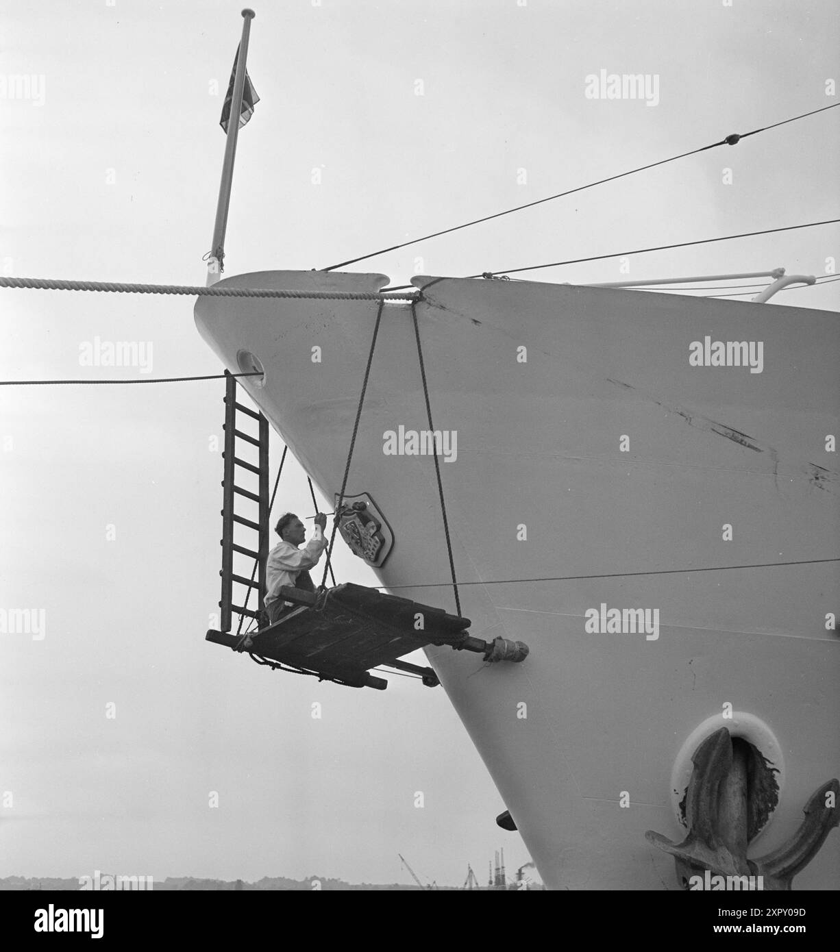 Aktuell 1948 : Kongeskipet kommer . Kongeskipet i Southampton for de siste oppgraderinger før skipet drar inn til Oslo og overlevering til kongen 9. juni. Helt for seg sjøl, langt borte fra ståket på dekkog under dekk, dingler Jimmy Johnston under baugen på «Norge», hvor han nettopp er i ferd Med å GI kongevåpenet det siste penselstrøk. Foto : Sverre A. Børretzen og E. Malandine / Aktuell / NTB ***Foto er ikke bildebehandlet*** le texte de cette image est traduit automatiquement Banque D'Images