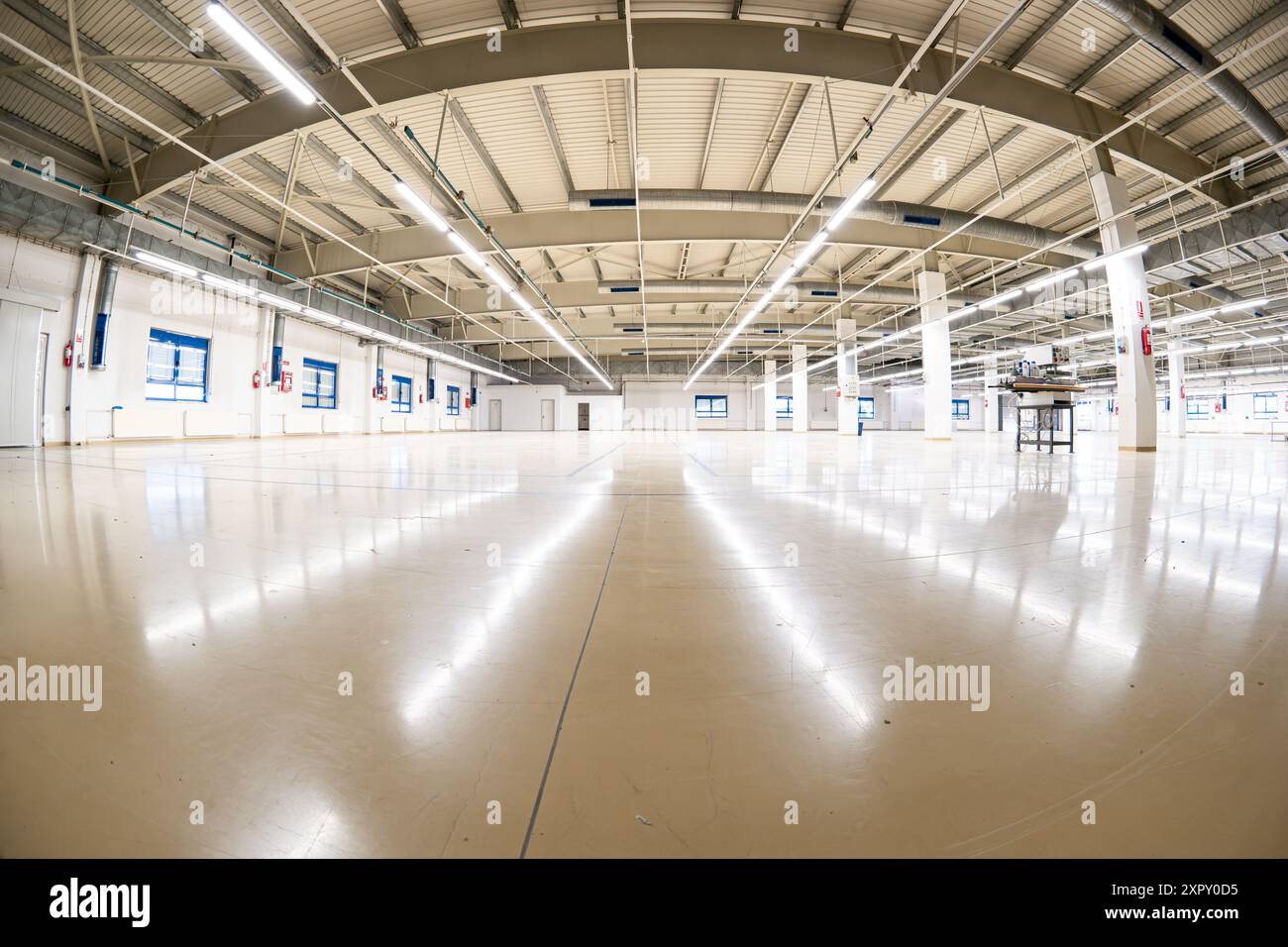 Hall de fabrication intérieur d'usine vide fermé avec plafond haut, poutres en béton. Prise de vue grand angle, lampes au néon montées au plafond, personne. Banque D'Images