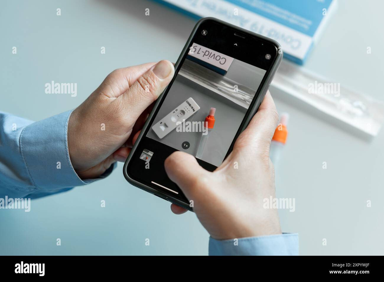 Mains féminines faisant une photo du kit d'auto-test avec un résultat positif covid 19 avec une caméra phoner à envoyer à un médecin. Kit de support d'auto-test Banque D'Images