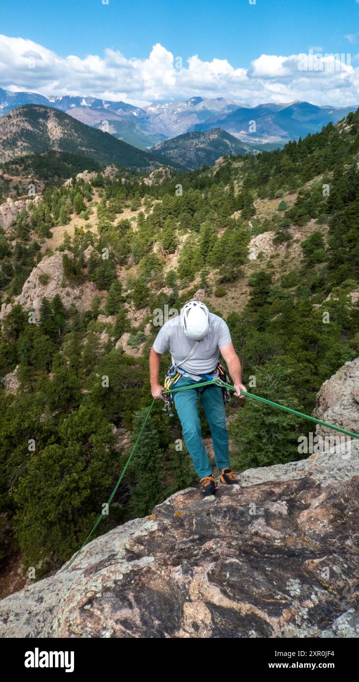 Un grimpeur adulte simple enroule une corde d'escalade pour se préparer à la descente en rappel depuis le sommet de Thumb Butte, Estes Park, Colorado Banque D'Images