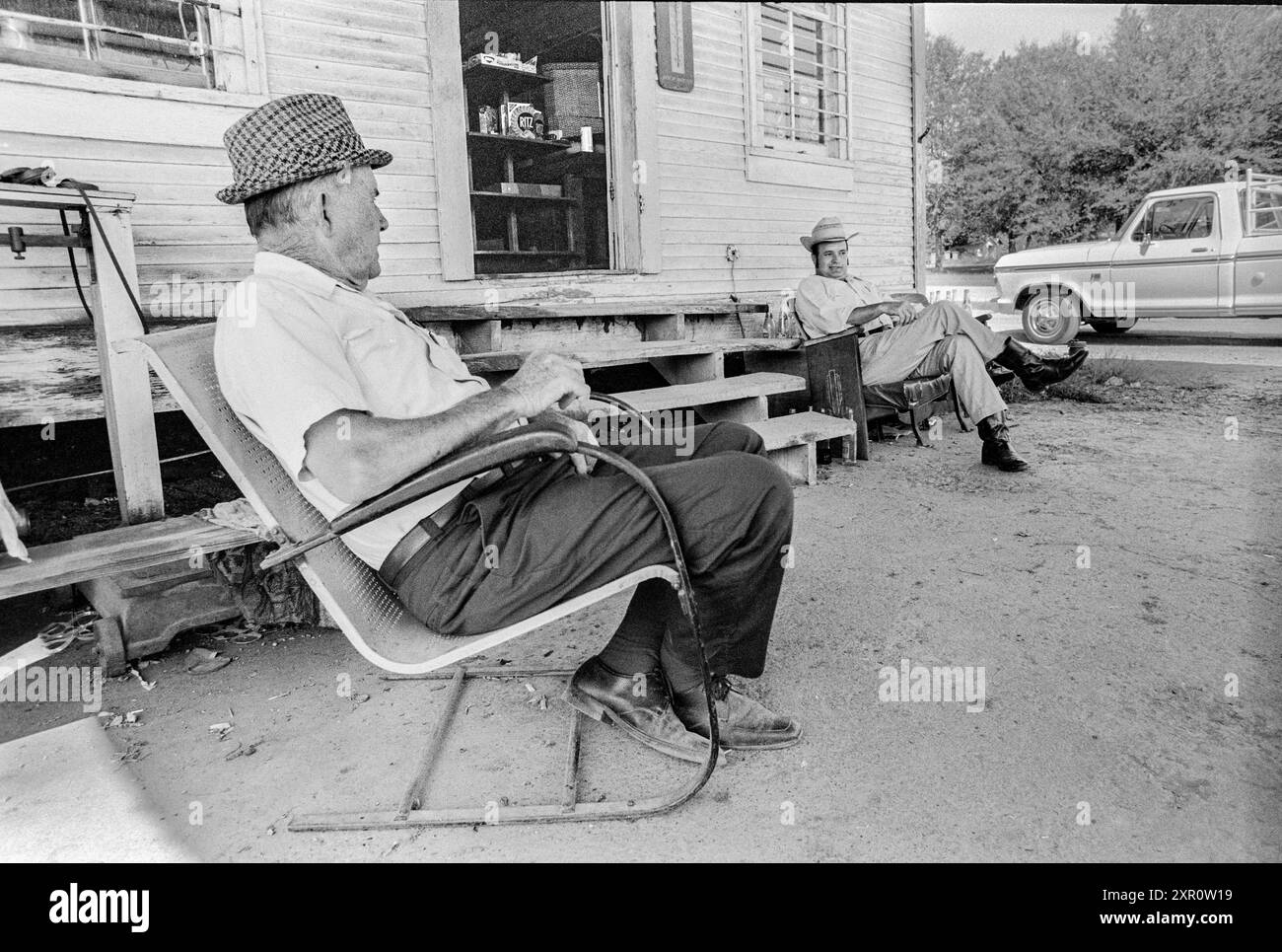 Macédoine, Arkansas, États-Unis – 23 juin 2024 : plan horizontal de deux hommes assis et parlant devant un vieux magasin des années 1970. Banque D'Images