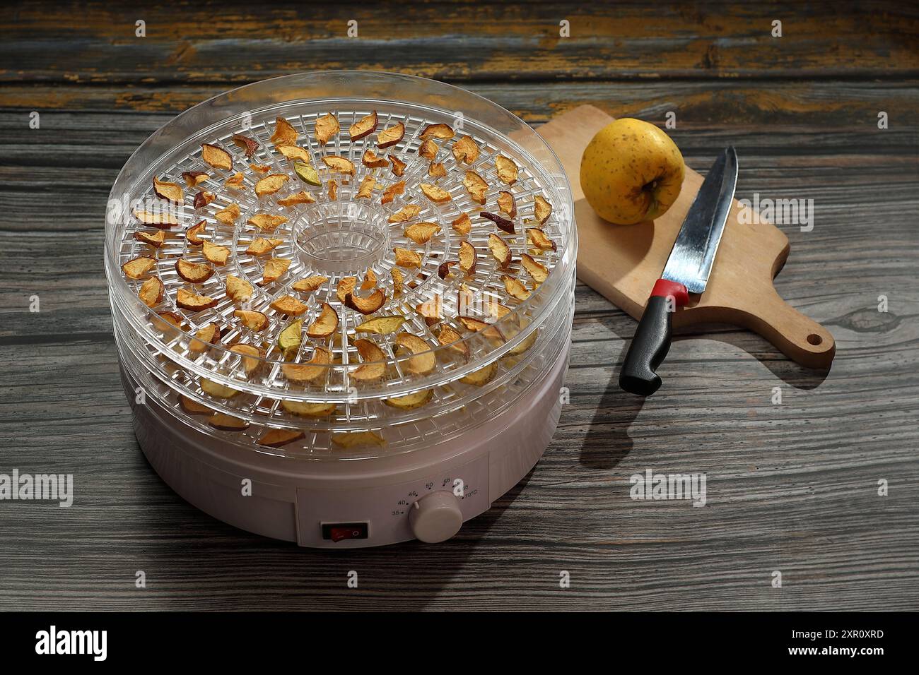 tranches de pommes séchées sur une grille de séchage et un couteau avec une pomme entière prête à préparer Banque D'Images