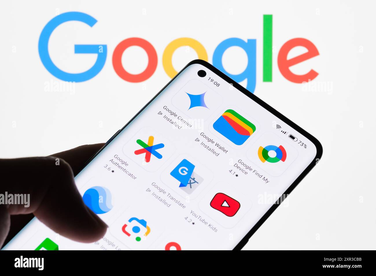 Gros plan d'un écran de smartphone affichant diverses applications Google avec le logo Google en arrière-plan, mettant en valeur la gamme d'applications développées par G. Banque D'Images