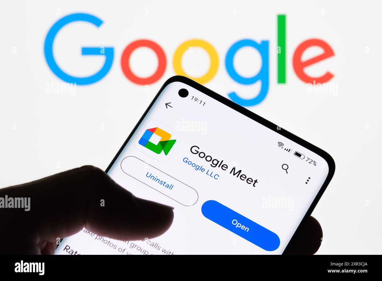 Gros plan de l'écran d'un smartphone affichant l'application Google Meet avec le logo Google en arrière-plan, mettant en évidence la connexion entre Google Meet et Goo Banque D'Images