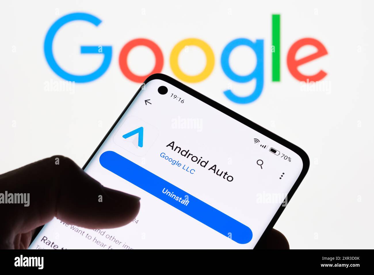 Gros plan de l'écran d'un smartphone affichant l'application Android Auto avec le logo Google en arrière-plan, illustrant la connexion entre Android Auto et G. Banque D'Images