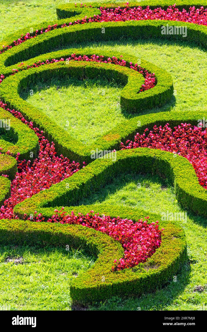 Détail du jardin fleuri ornemental en fleurs avec fleurs rouges en fleurs, arbustes verts et pelouse, journée ensoleillée d'été, jardin fleuri de l'UNESCO à Kroměříž Banque D'Images