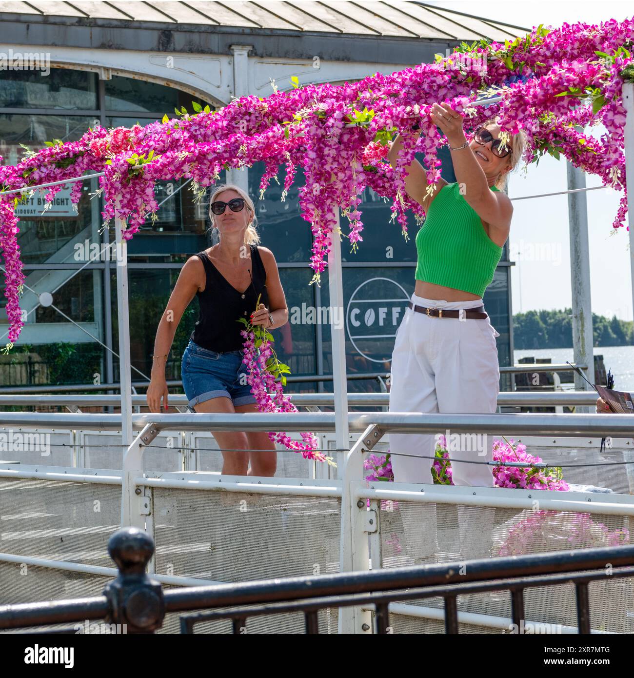Deux belles femmes en lunettes de soleil, décorer le coin salon extérieur de leur café avec des fleurs. Cardiff Bay, Cardiff. ROYAUME-UNI. Banque D'Images