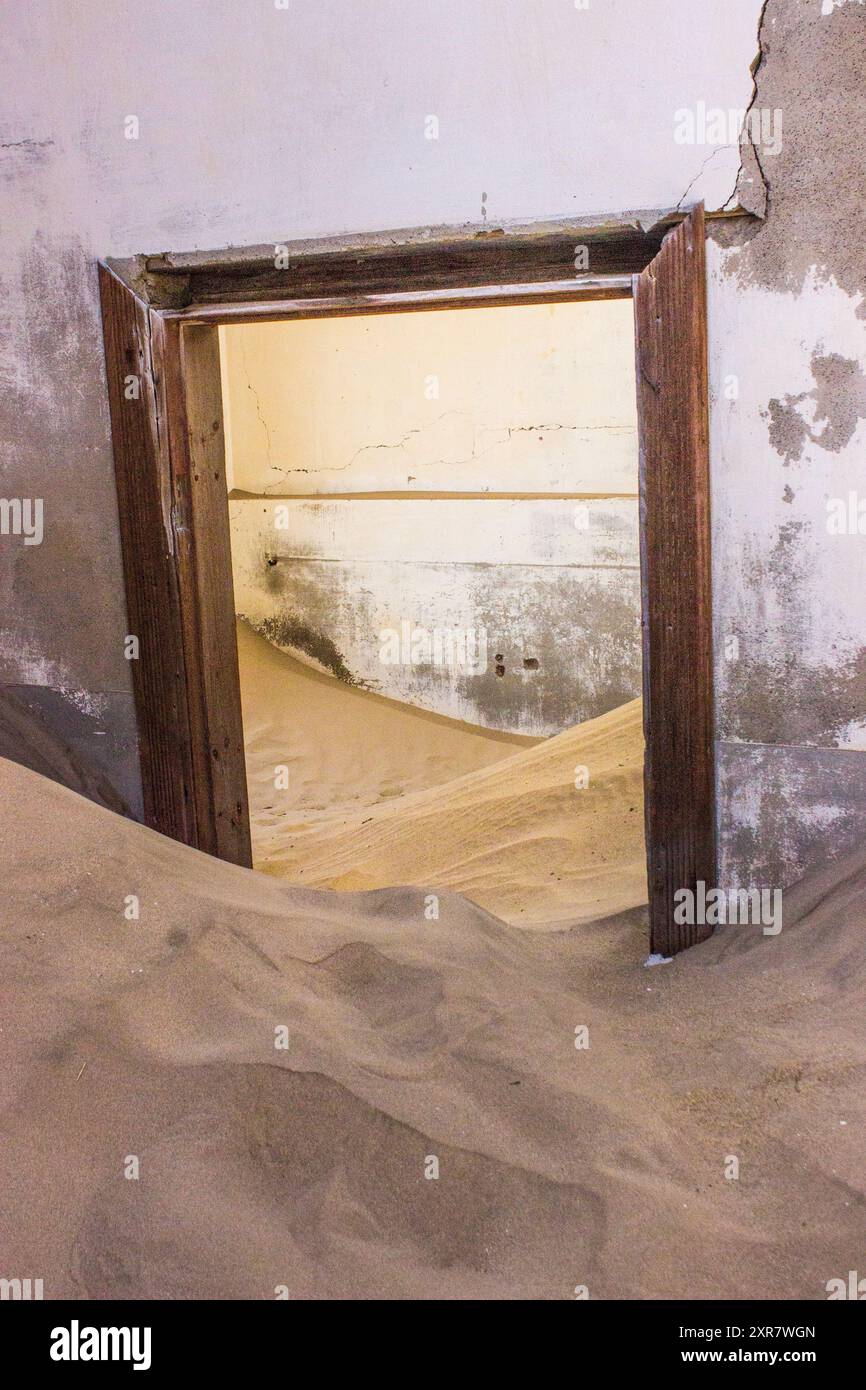 Porte à moitié enterrée dans le sable dans l'un des bâtiments abandonnés de la ville fantôme de Kolmannskuppe en Namibie. Banque D'Images