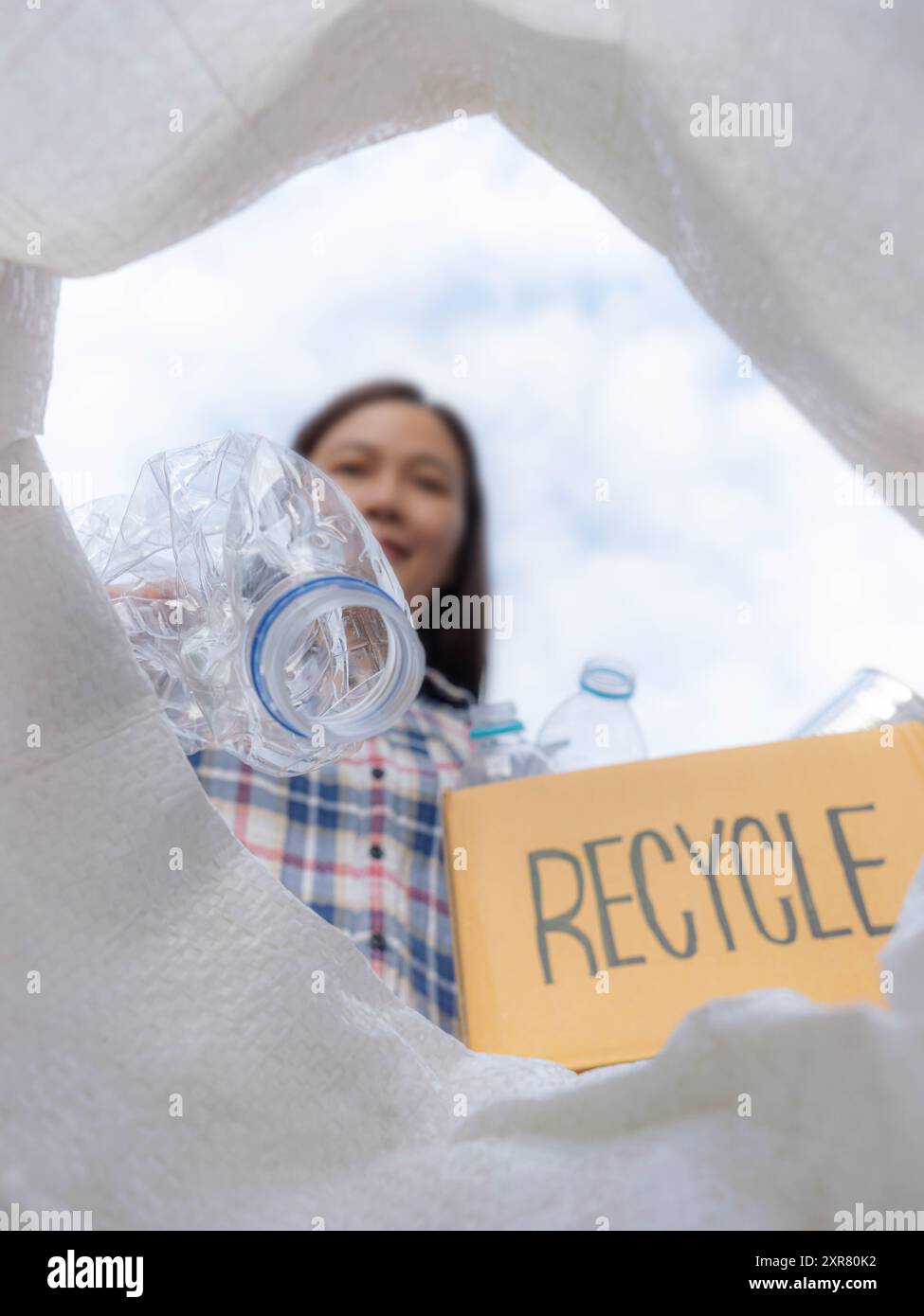 Femme asiatique tient une boîte à cartes avec le logo de recyclage qui trie les ordures pour séparer les ordures pour le recyclage, jette différents types de bouteille dans une poubelle Banque D'Images