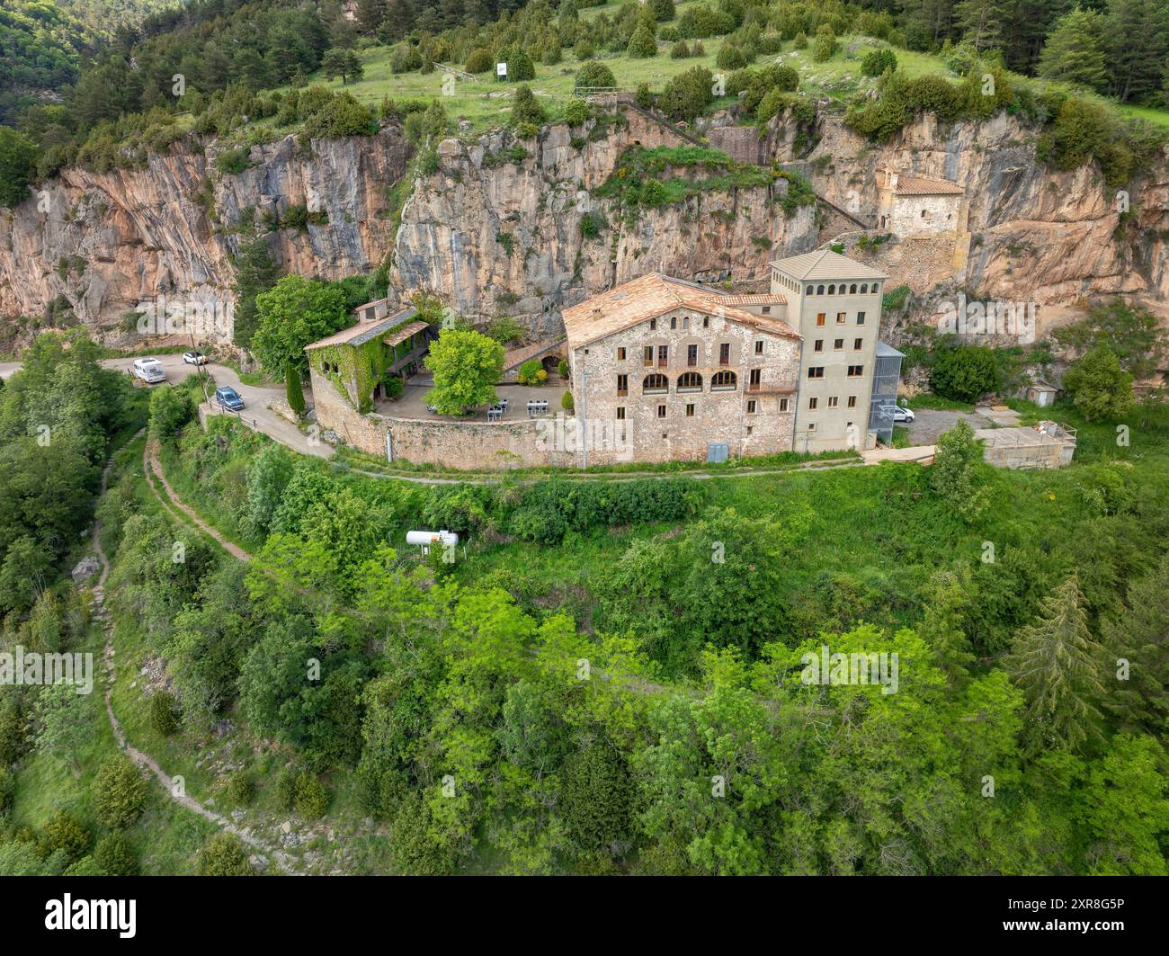 Vue aérienne du sanctuaire de Montgrony construit au pied d'une falaise dans la chaîne montagneuse de Montgrony (Ripollès, Gérone, Catalogne, Espagne, Pyrénées) Banque D'Images