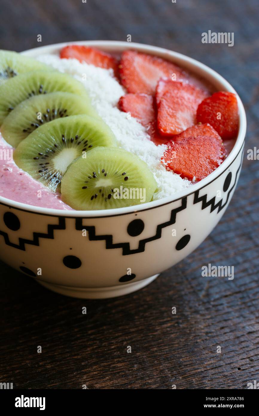 Bol à smoothie aux fraises avec tranches de kiwi, fraises et flocons de noix de coco. Banque D'Images