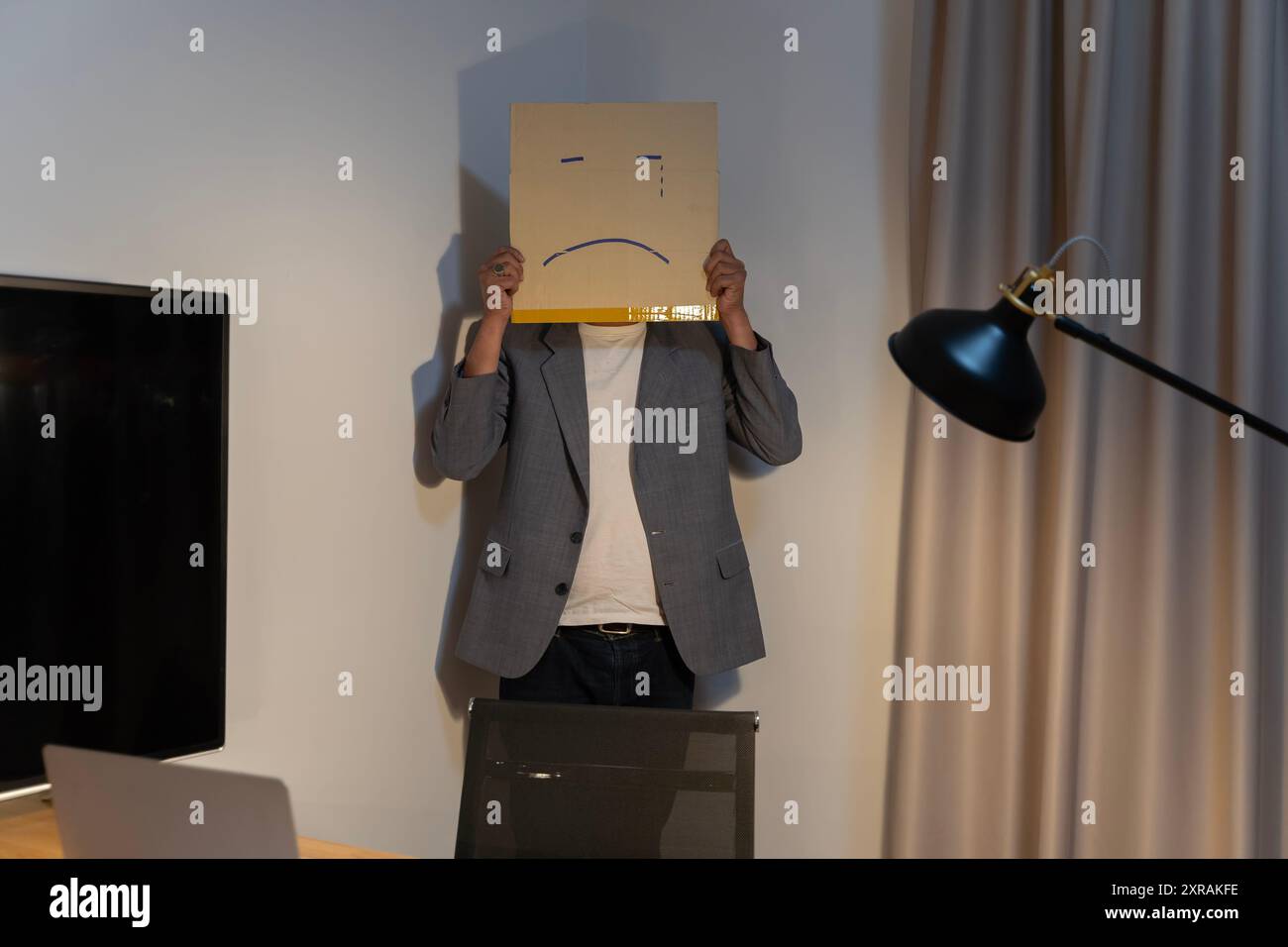 Portrait d'un homme d'affaires couvrant son visage avec un masque en papier avec un visage triste, dessiné dessus mauvaise dépression négative de la personne anonyme dans la co Banque D'Images