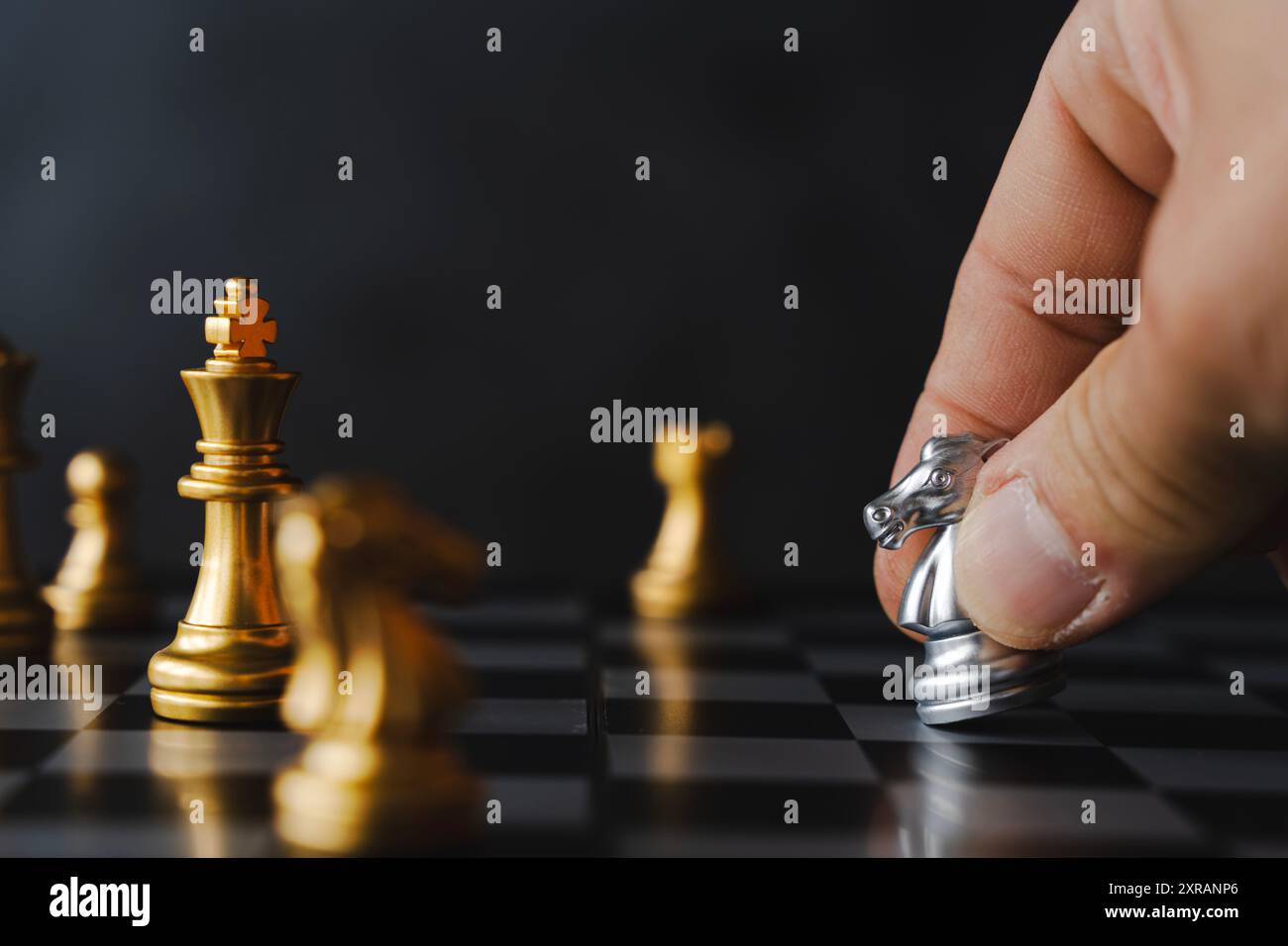 Pièce d'échecs noire Knight sur échiquier. Les mains d'un homme d'affaires déplacent une figure d'échecs dans un tournoi réussi joué. Stratégie de gestion ou leade Banque D'Images