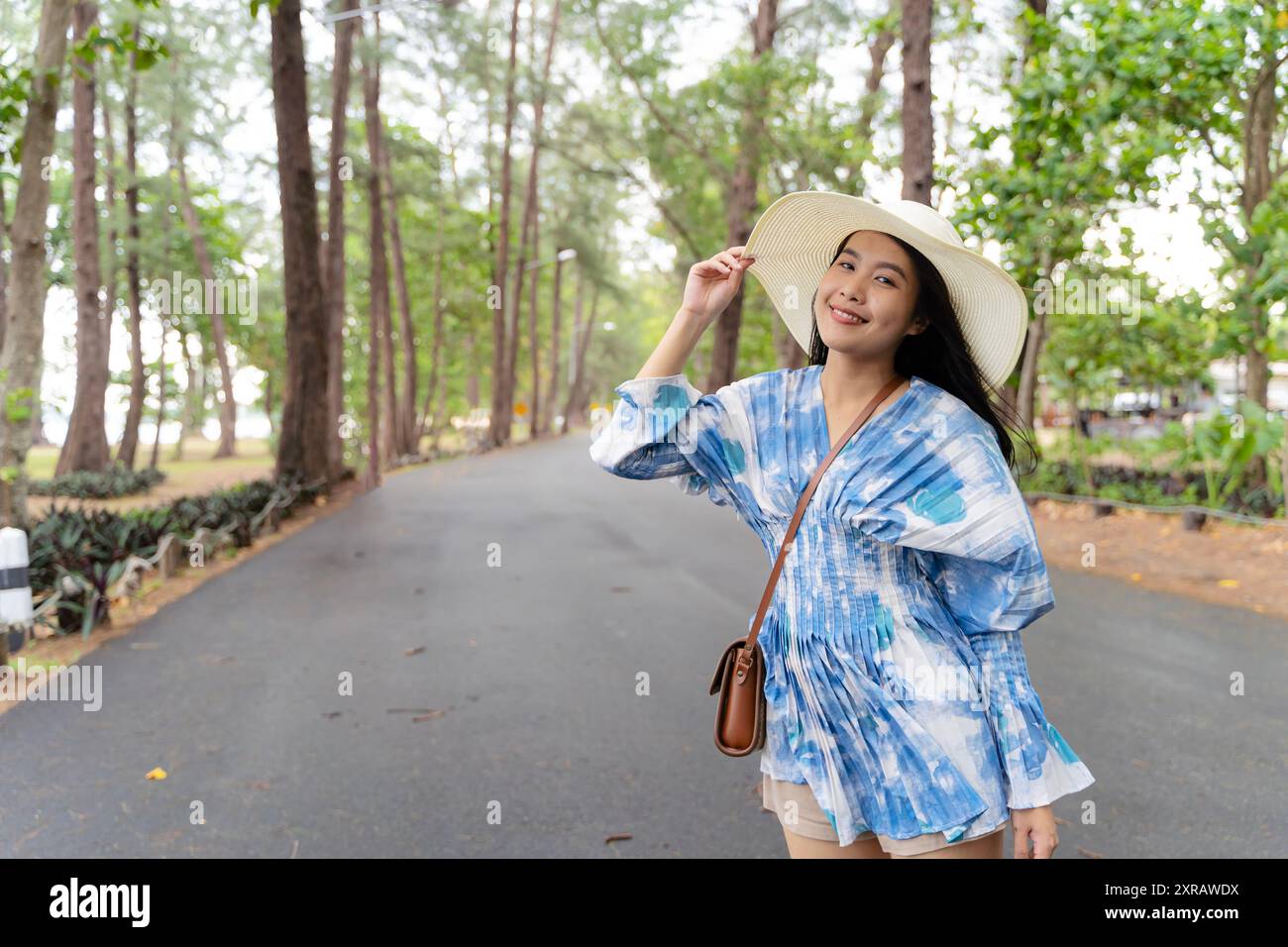 Portrait de jeune voyageuse asiatique avec chapeau de tissage et panier et un appareil photo sur fond vert de nature de parc public. Voyage voyage style de vie, monde Banque D'Images