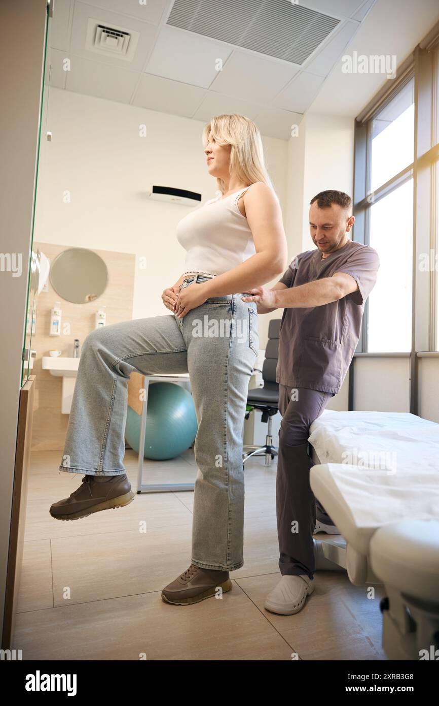 Un professionnel de santé effectuant une palpation lombaire chez une femme adulte Banque D'Images