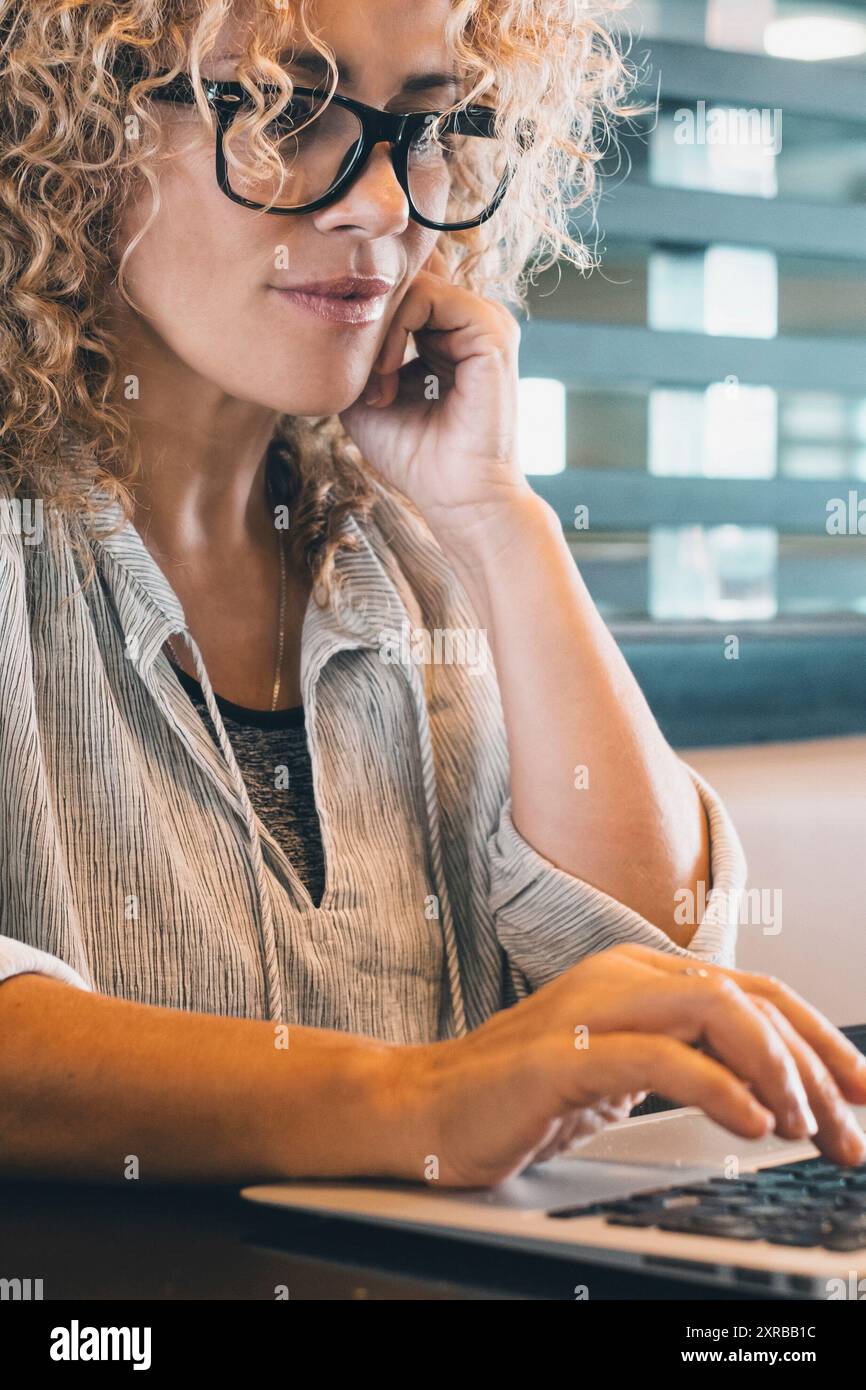 Femme attrayante travaillant sur un ordinateur portable au bureau dans un espace de travail ou un bureau moderne. Femme d'affaires moderne et branchée utilisant l'ordinateur seul pour un travail en ligne. P Banque D'Images