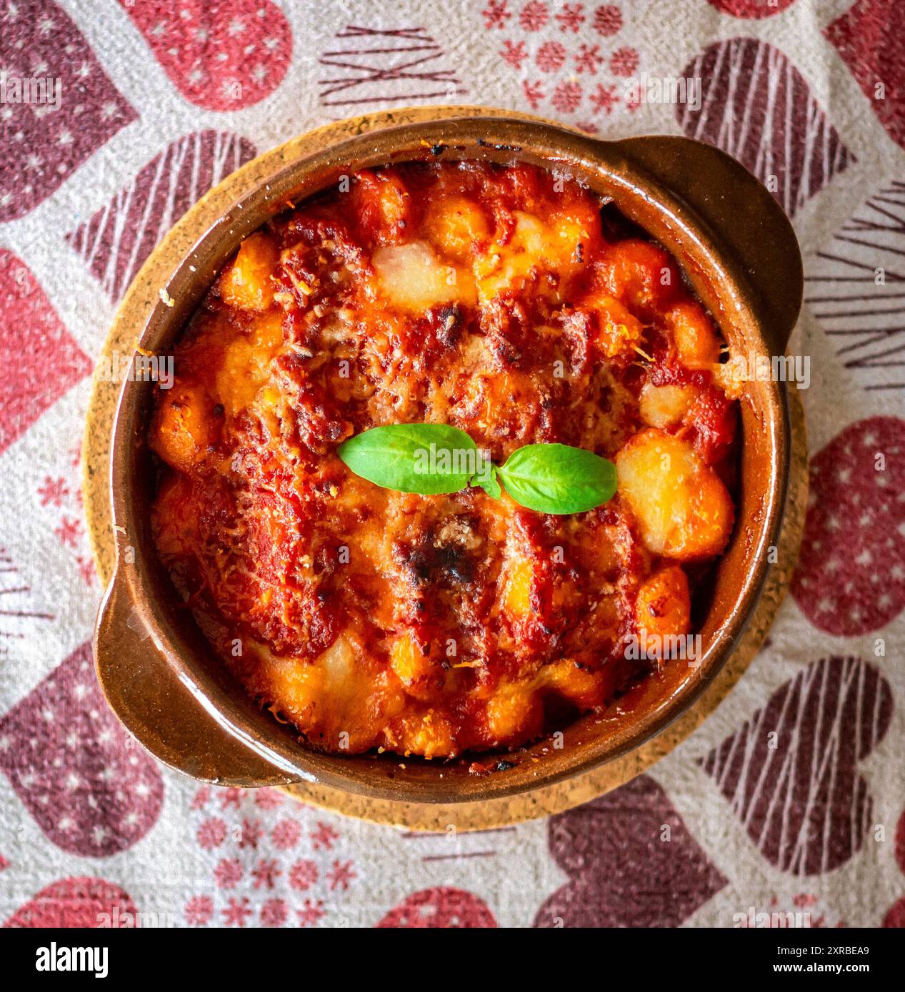 Gnocchi alla Sorrentina, boulettes de pommes de terre italiennes à la sauce tomate, gratinées avec du fromage mozzarella dans un plat en terre cuite. Banque D'Images