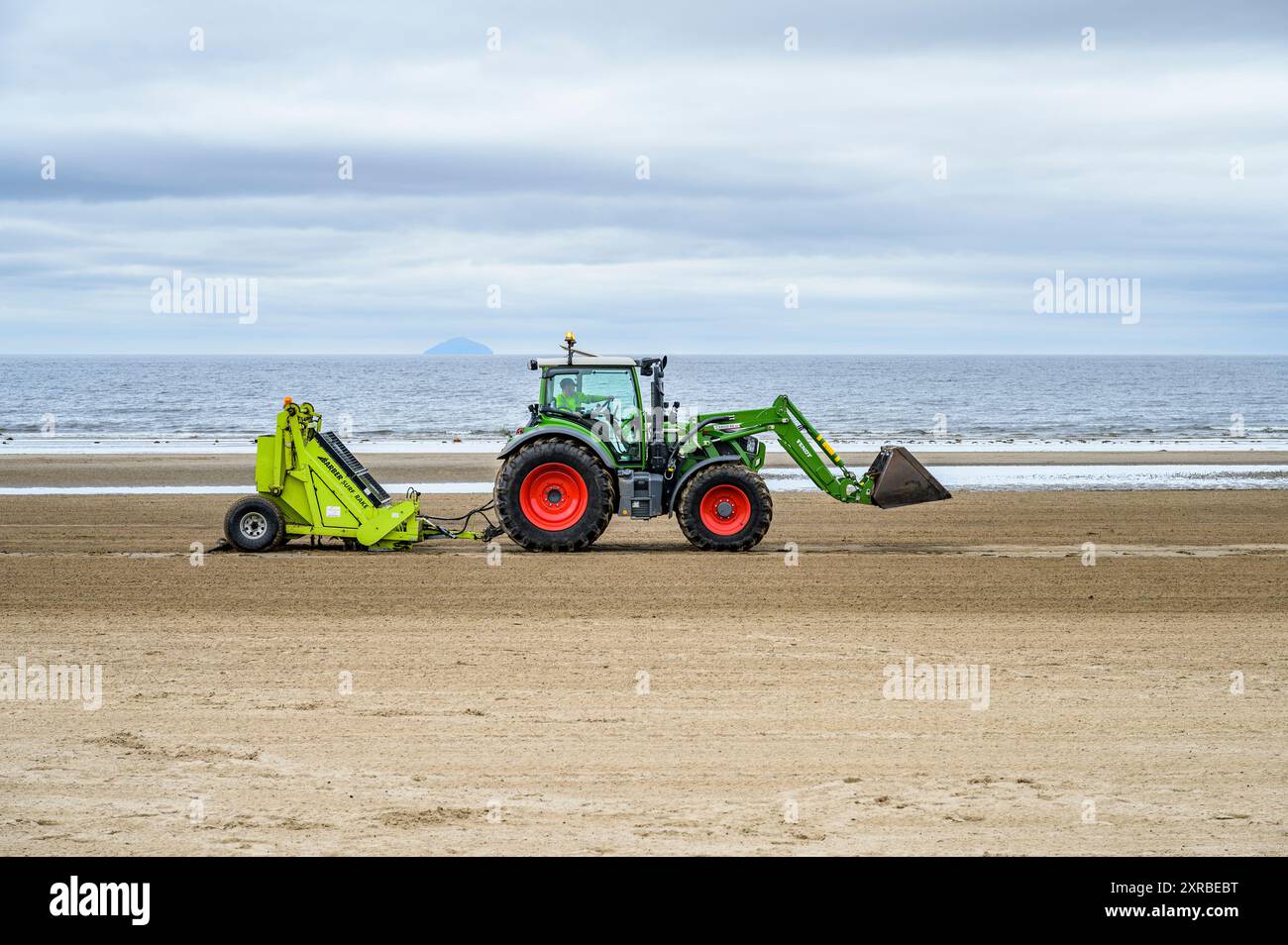 Les débris sont éliminés avec un tracteur Fendt remorquant un râteau de surf Barber sur South Beach, Troon, South Ayrshire, Écosse, Royaume-Uni, Europe Banque D'Images