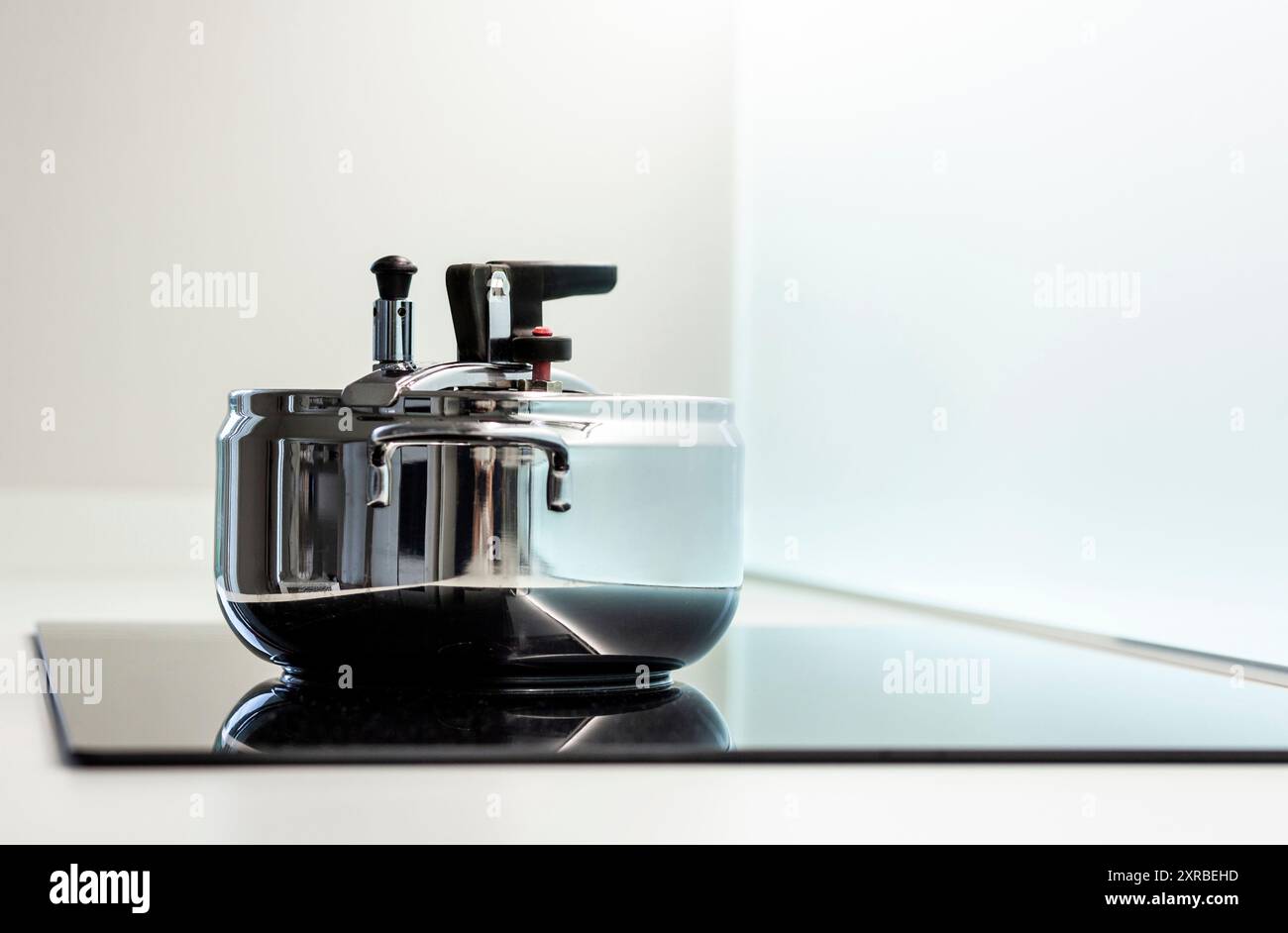 Autocuiseur en acier inoxydable sur une plaque de cuisson à induction moderne. Banque D'Images