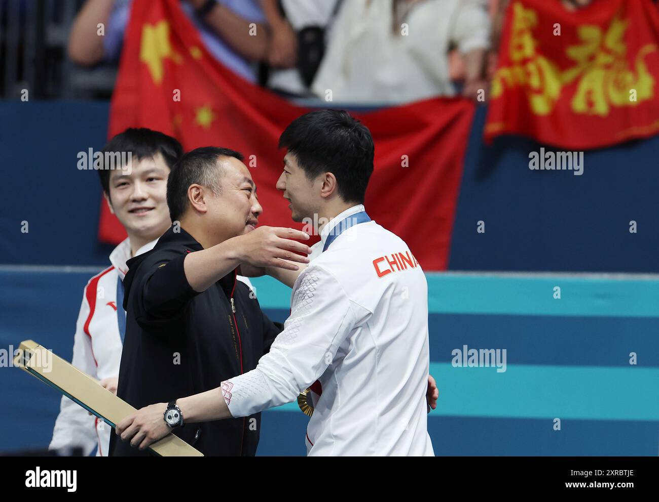 Paris, France. 9 août 2024. Liu Guoliang (C), président de l'Association chinoise de tennis de table, embrasse avec la médaillée d'or ma long (R) de l'équipe de Chine après la cérémonie de victoire de l'équipe masculine de tennis de table aux Jeux Olympiques de Paris 2024 à Paris, France, le 9 août 2024. Crédit : Liu Xu/Xinhua/Alamy Live News Banque D'Images
