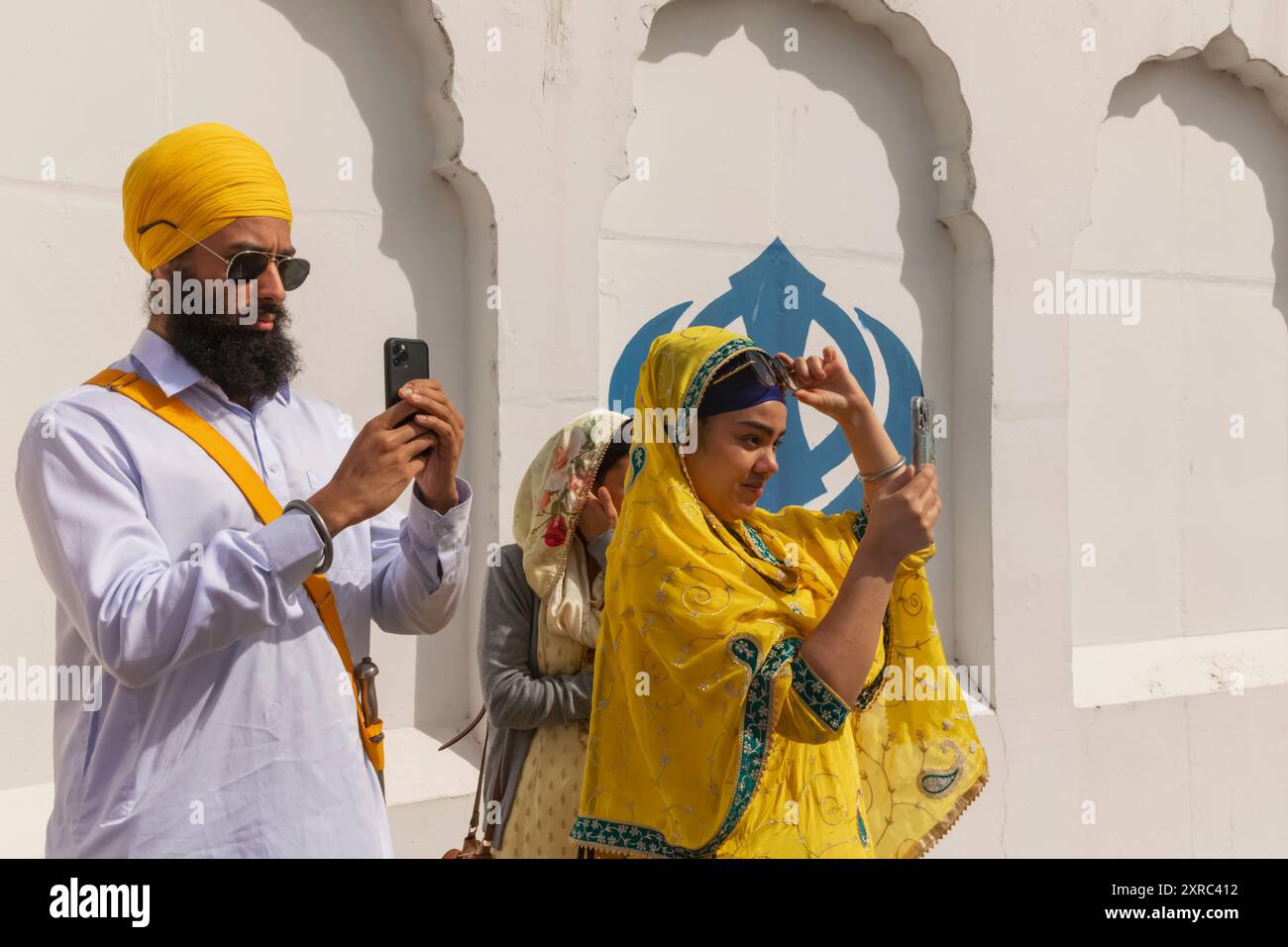 Angleterre, Kent, Gravesend, le Guru Nanak Darbar Gurdwara, le festival annuel Vaisakhi aka Baisakhi tenu le 13 avril, couple sikh prenant des photos avec des iPhones Banque D'Images