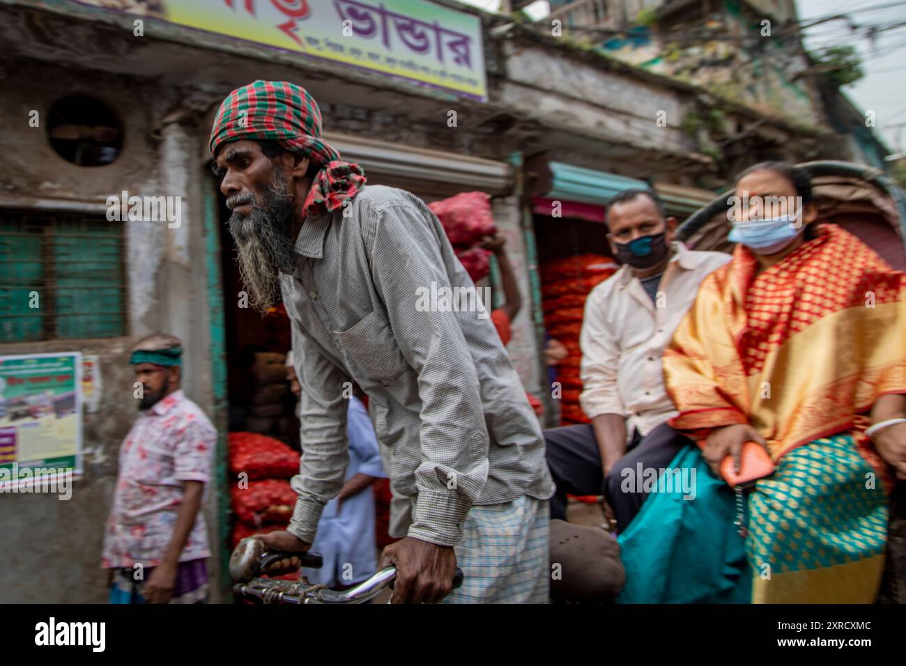 Des tireurs de pousse-pousse dans les rues de Puran Dhaka - Old Dhaka au Bangladesh. Les pousse-pousse sont des tricycles à pédale, mais utilisés pour être tirés à la main, d'où 'arrache-pousse'. Aujourd'hui, beaucoup de pousse-pousse sont même convertis pour être alimentés par moteur électrique. Banque D'Images