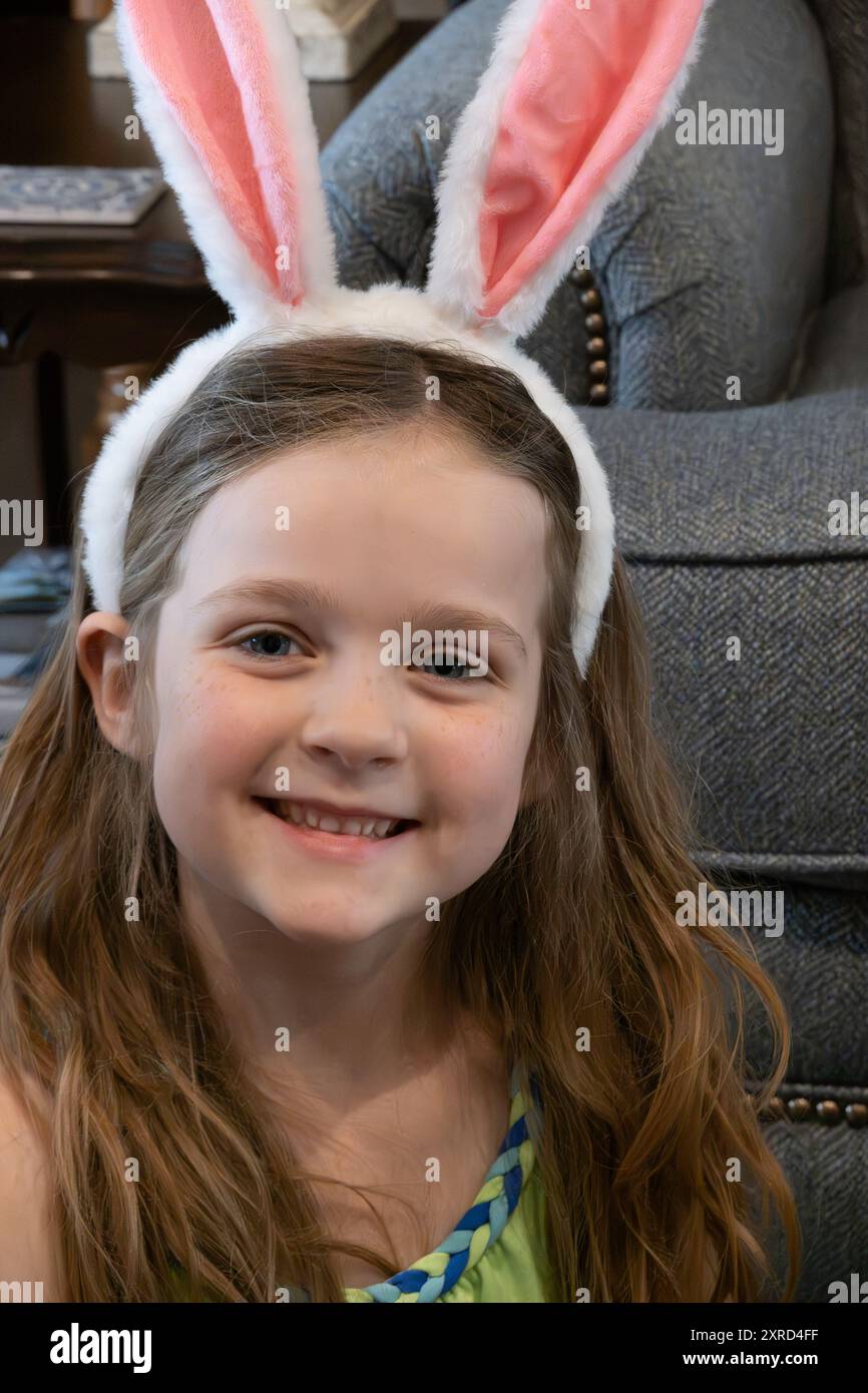 Fille de 6 ans portant des oreilles de lapin sourit joyeusement le dimanche de Pâques. ÉTATS-UNIS Banque D'Images