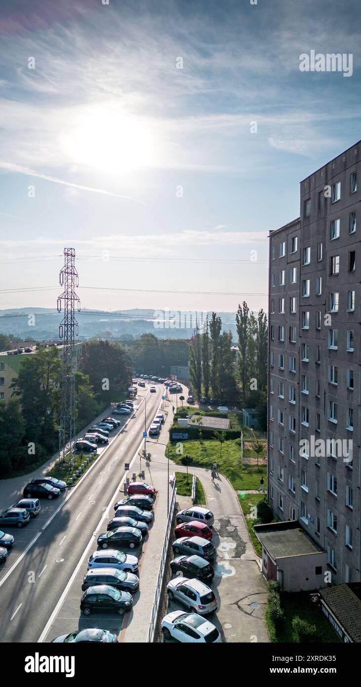 Vue matinale sur une rue animée avec des voitures garées et un immeuble résidentiel contre un ciel ensoleillé dans un cadre urbain Banque D'Images