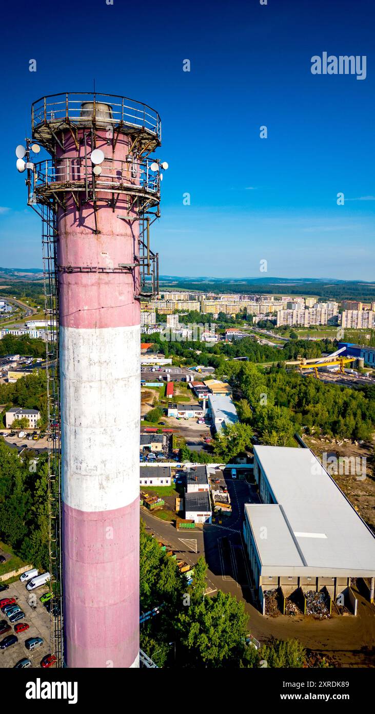 Vue aérienne d'un smokestack industriel rose et blanc avec antennes 5g au milieu de la ville urbaine Banque D'Images