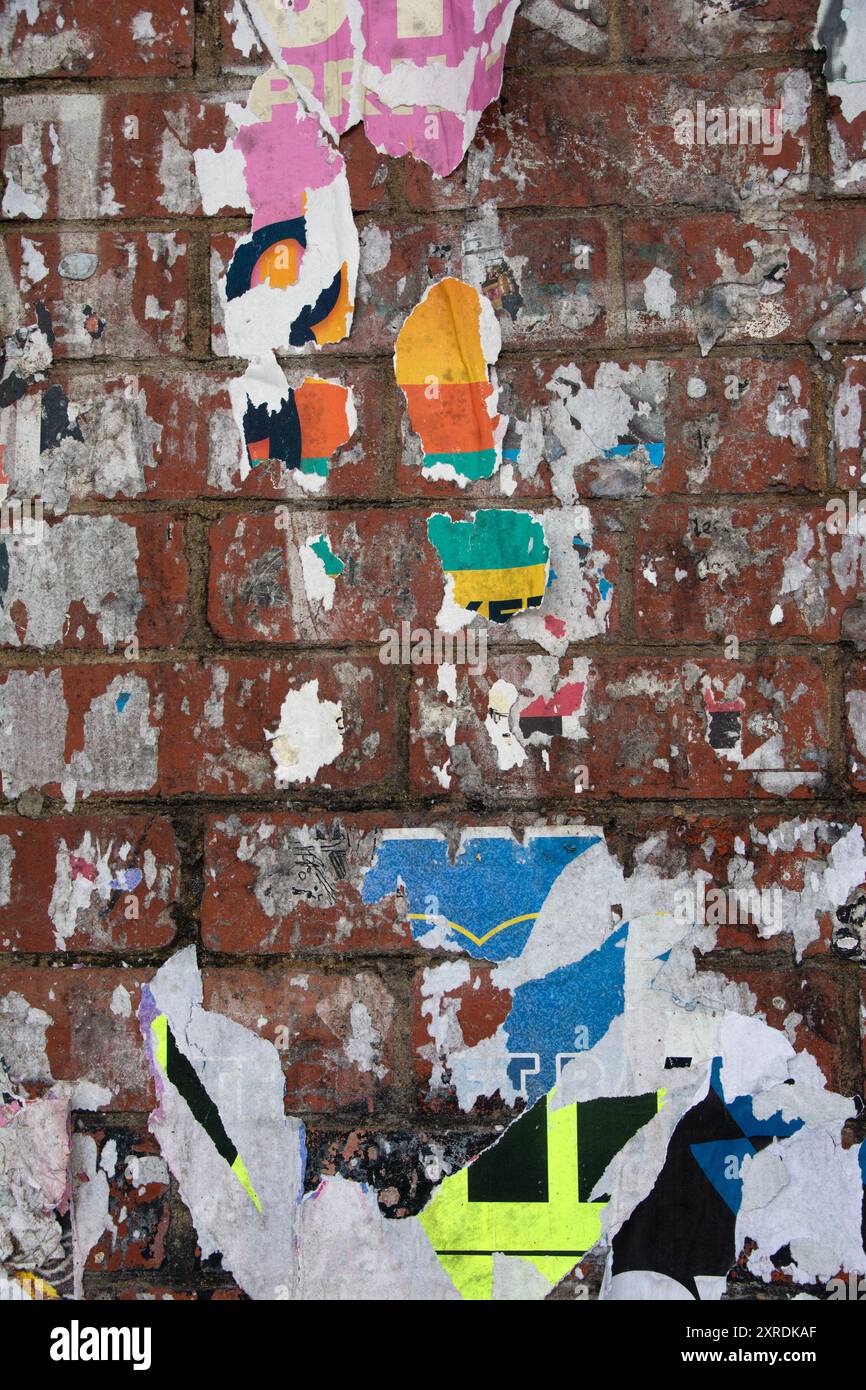 gros plan d'un mur de briques recouvert de couches d'affiche publicitaire déchirée et pelée Banque D'Images