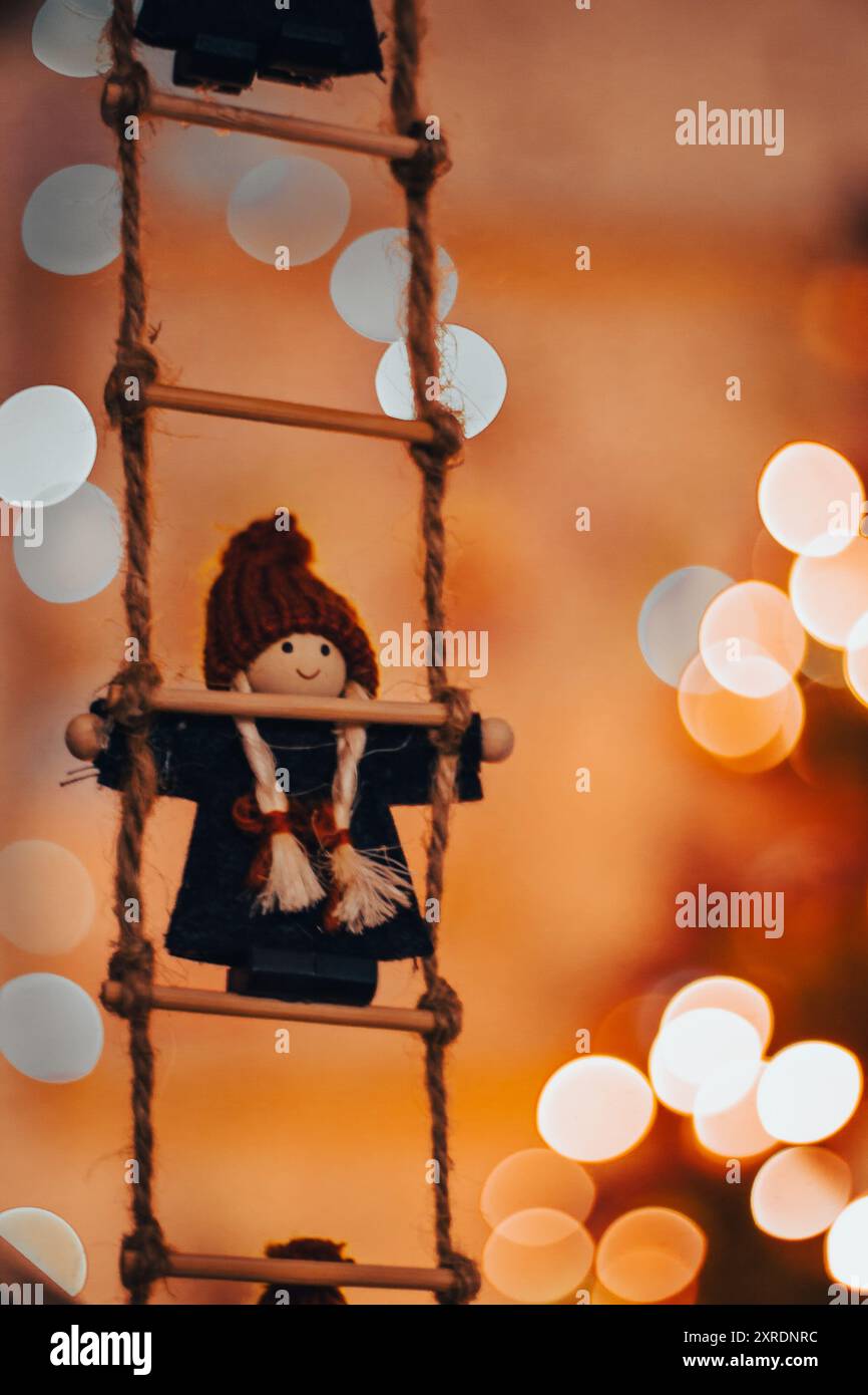 Poupée de Noël sur échelle de corde sur fond de lumières chaudes. Esprit de Noël. Décoration scandinave. Décoration d'hiver confortable. Heure de Noël. Jouet nordique. Banque D'Images