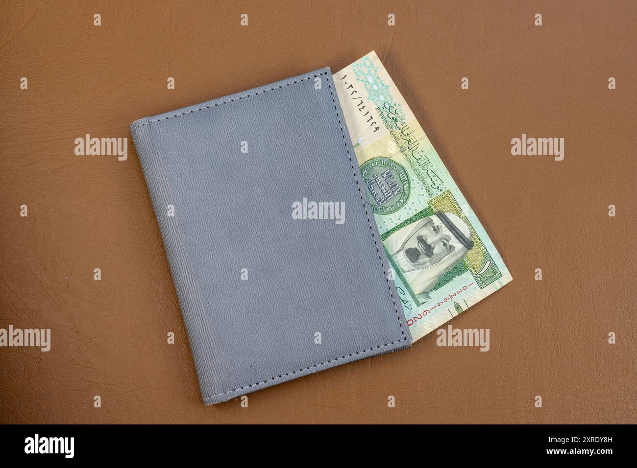 Monnaie riyal saoudienne dans un portefeuille gris sur une surface en cuir. Gros plan. Banque D'Images