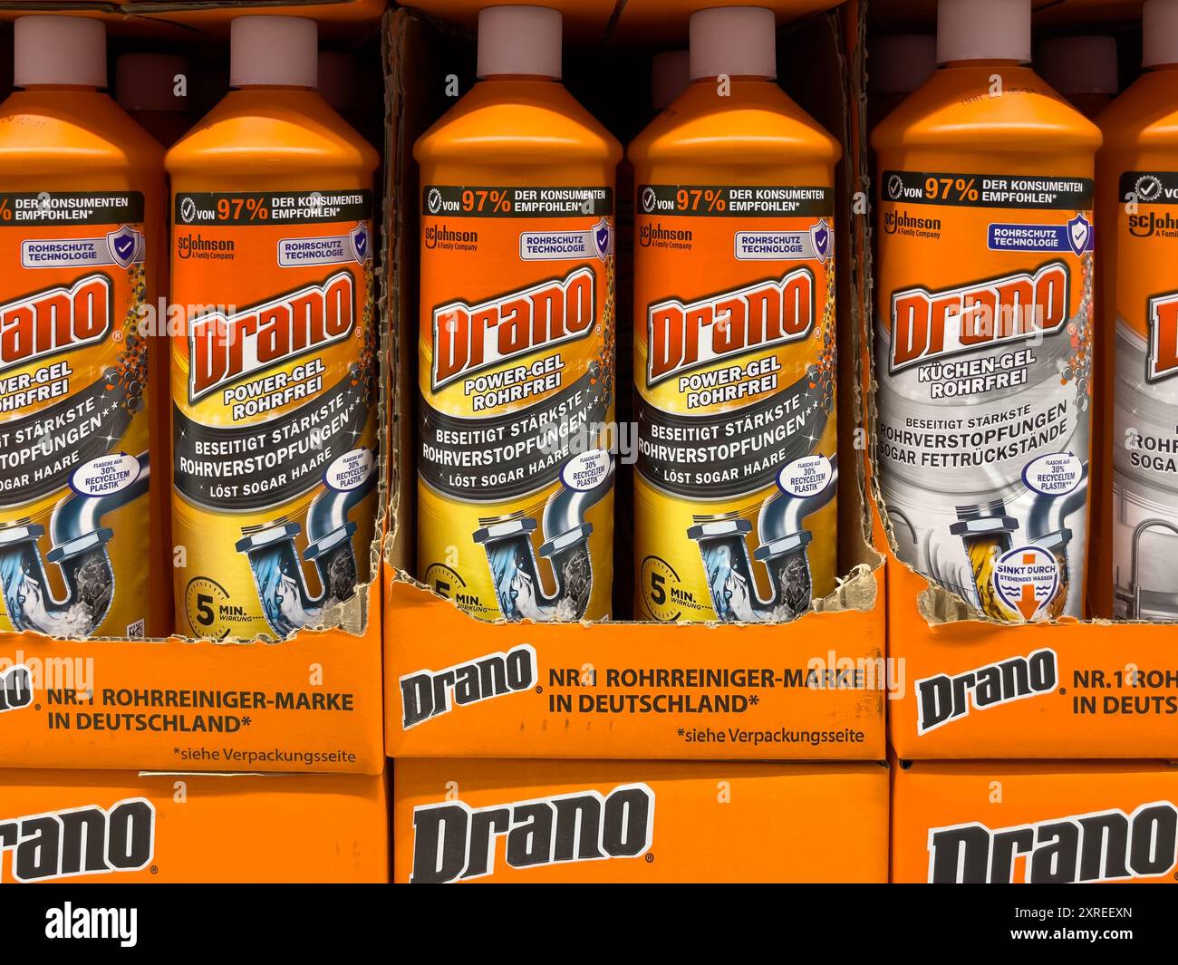 Une rangée de bouteilles orange de nettoyant pour drain Drano s'affiche. Les bouteilles sont alignées, certaines plus grandes que d'autres. Banque D'Images