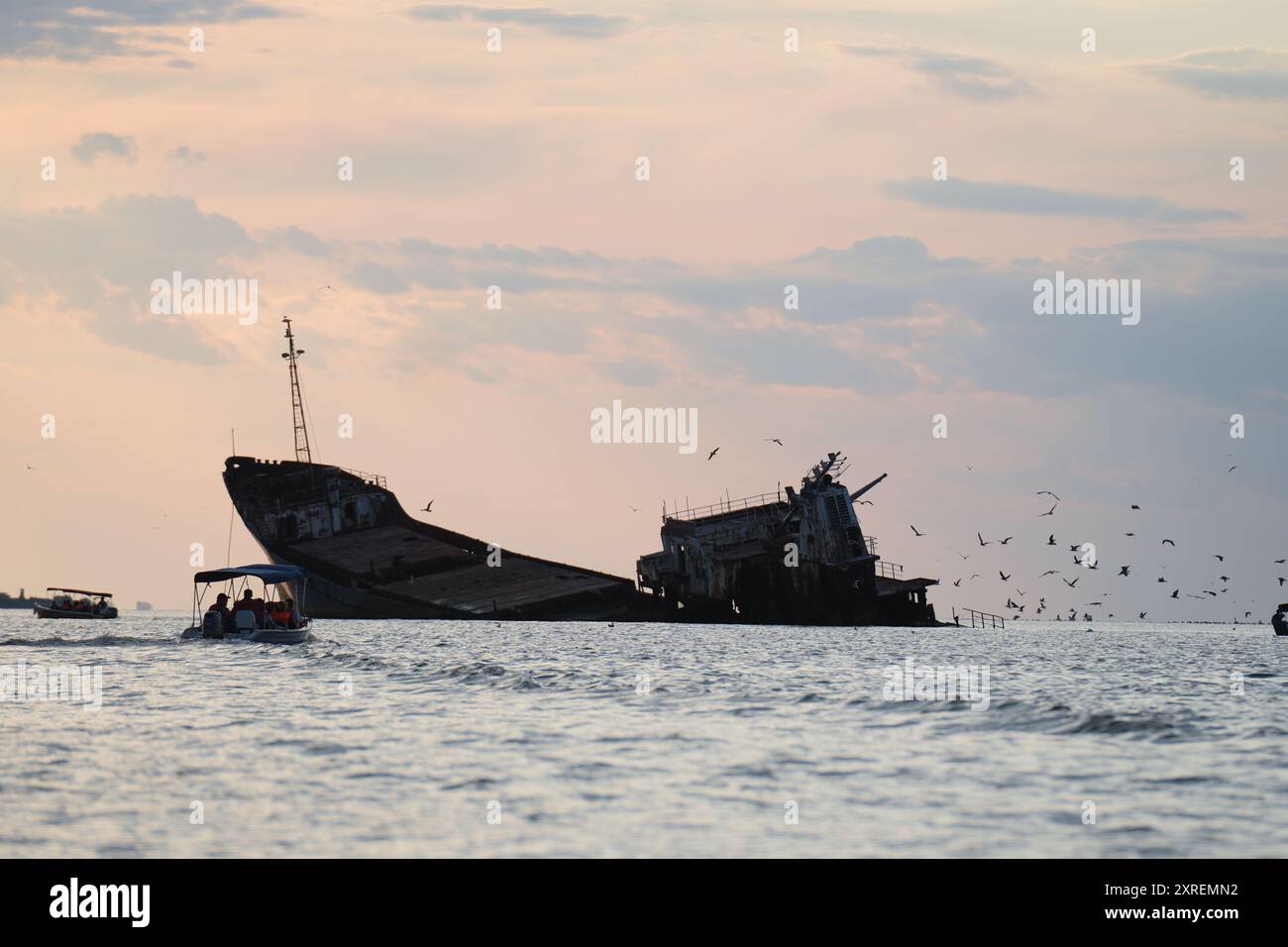 Bateaux touristiques et mouettes entourant l'épave de Sulina au coucher du soleil, mer Noire, Roumanie Banque D'Images