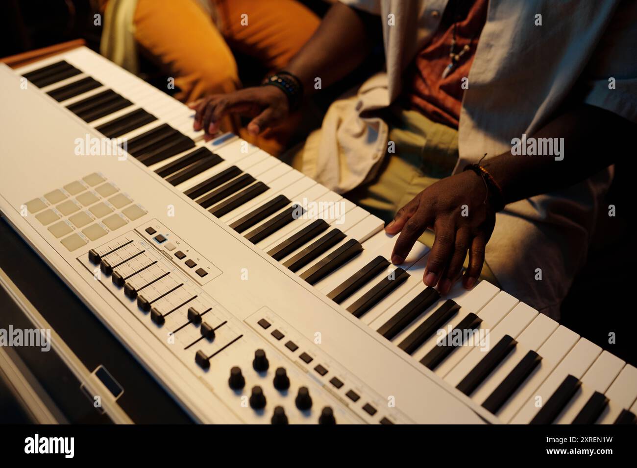 Personne jouant le clavier avec les mains sur le clavier et les ajustements sur le contrôleur MIDI dans le studio de musique. Capturer la créativité grâce à la performance musicale Banque D'Images