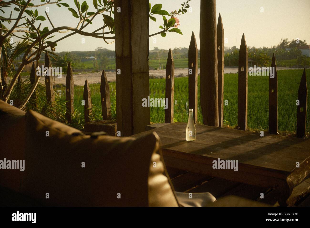 Une terrasse patio en bois équipée de meubles de jardin, y compris une chaise de sac de haricots et une table rustique en bois, avec une vue sur les rizières, frangip Banque D'Images