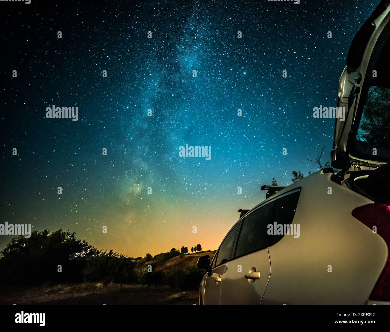 Paysage de nuit avec voiture blanche contre la voie lactée du ciel Banque D'Images
