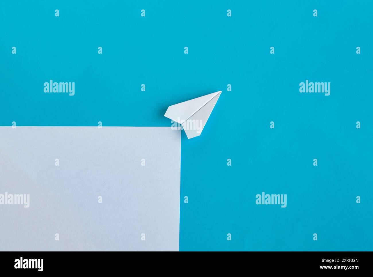 Vue de dessus de l'avion de papier blanc volant le long de la route sur fond bleu avec un espace personnalisable pour le texte. Banque D'Images