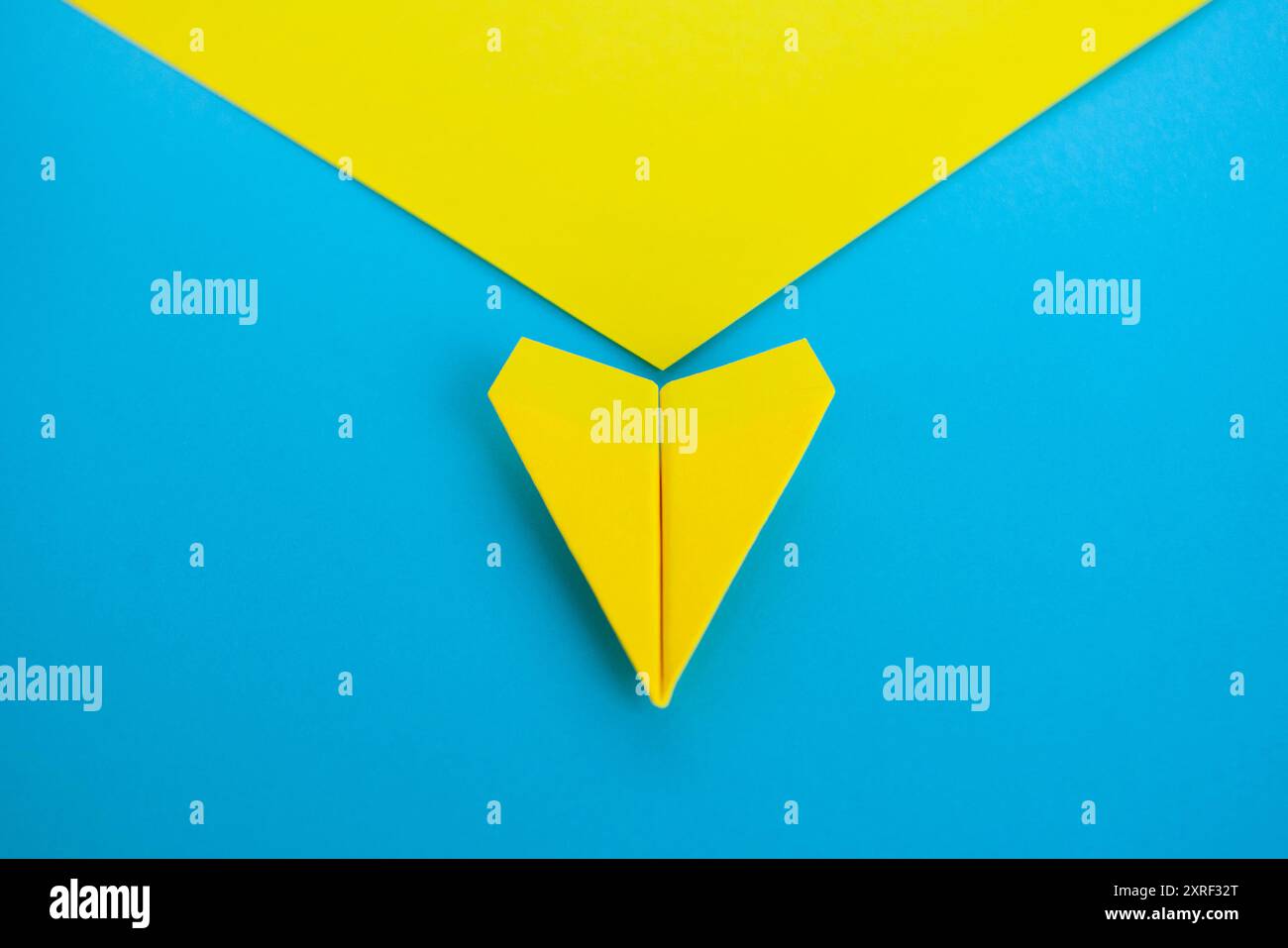 Gros plan vue de dessus de l'avion de papier jaune volant le long de la route sur fond bleu. Banque D'Images