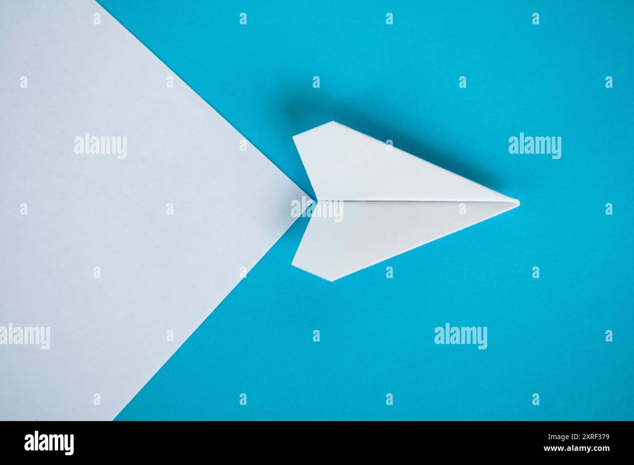 Vue de dessus de l'avion de papier blanc volant le long de la route sur fond bleu. Banque D'Images