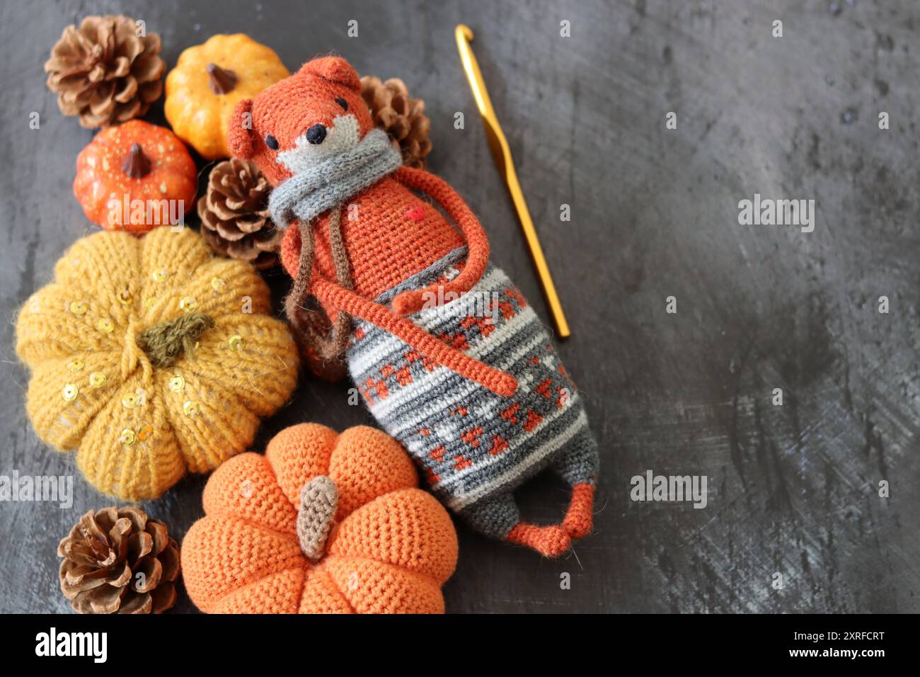 Décoration d'Halloween avec des citrouilles, jouet Fox crocheté et fil de laine orange sur fond gris avec espace pour le texte. Cadeau d'automne fait à la main. Banque D'Images