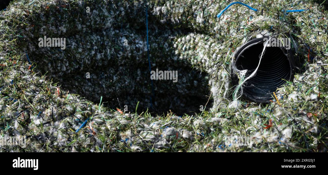 Tuyau de drainage en plastique enroulé enveloppé de fibres de gazon artificiel, produit à partir de déchets résiduels provenant de champs de gazon artificiel usagés Banque D'Images