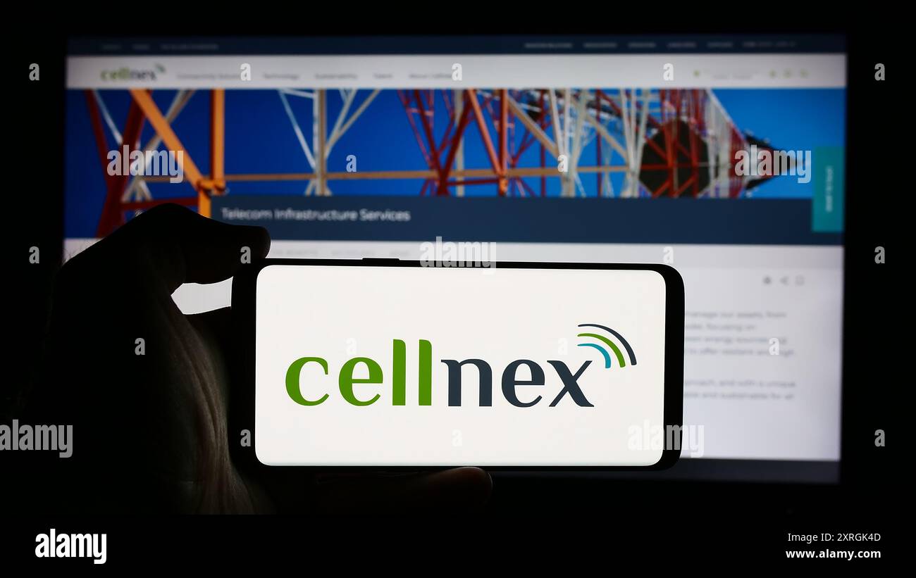 Personne tenant le téléphone portable avec le logo de la société espagnole de télécommunications Cellnex Telecom sa en face de la page Web de l'entreprise. Concentrez-vous sur l'affichage du téléphone. Banque D'Images