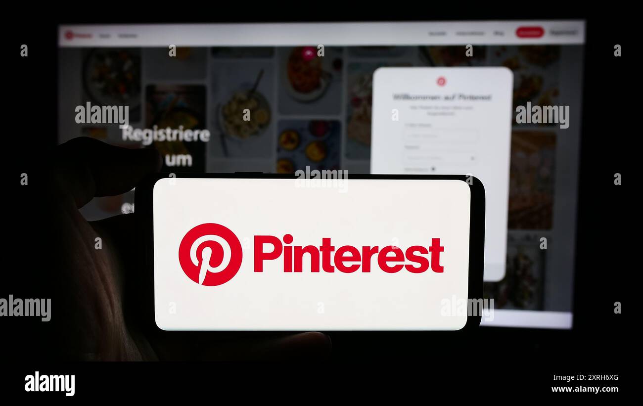Personne tenant un téléphone portable avec le logo de la société de médias sociaux américaine Pinterest Inc devant la page Web de l'entreprise. Concentrez-vous sur l'affichage du téléphone. Banque D'Images