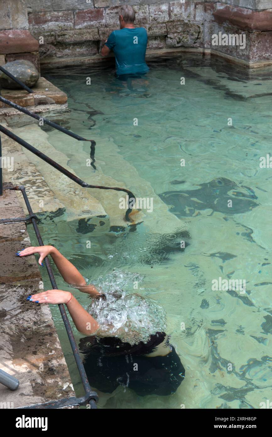 Sanctuaire St Winefrides et puits sacré. Pèlerinage catholique le jour de la fête de Saint Winefride le 22 juin. Dans la piscine extérieure, une jeune femme s'agenouille sur une pierre submergée, connue sous le nom de pierre de Saint Beuno, aussi longtemps qu'il le faut pour terminer la prière du Rosaire. Ayant marché autour de la piscine extérieure trois fois dans l'espoir d'un remède miracle. Holywell, Flintshire Wales, Royaume-Uni des années 1990 HOMER SYKES Banque D'Images