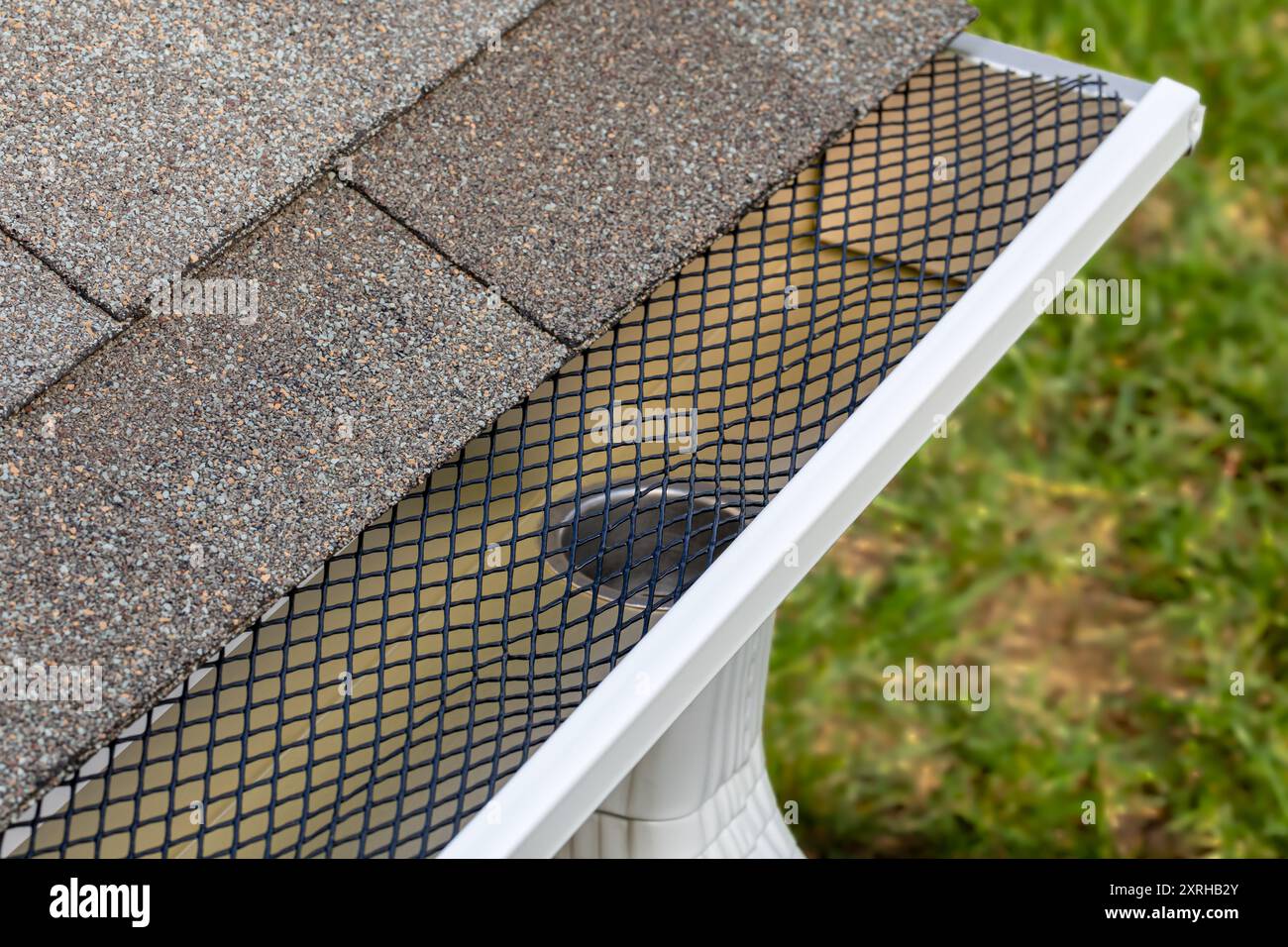 Installation d'un tamis à mailles de protection de gouttière sur une gouttière de pluie. Entretien de la maison, travaux de triage et concept de dommages au toit Banque D'Images