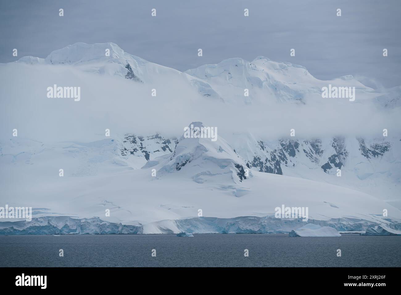 Magnifique paysage Antarctique avec nuages bas. Montagnes couvertes de neige douce et intacte. Photographie de la nature à distance. Changement climatique. Banque D'Images