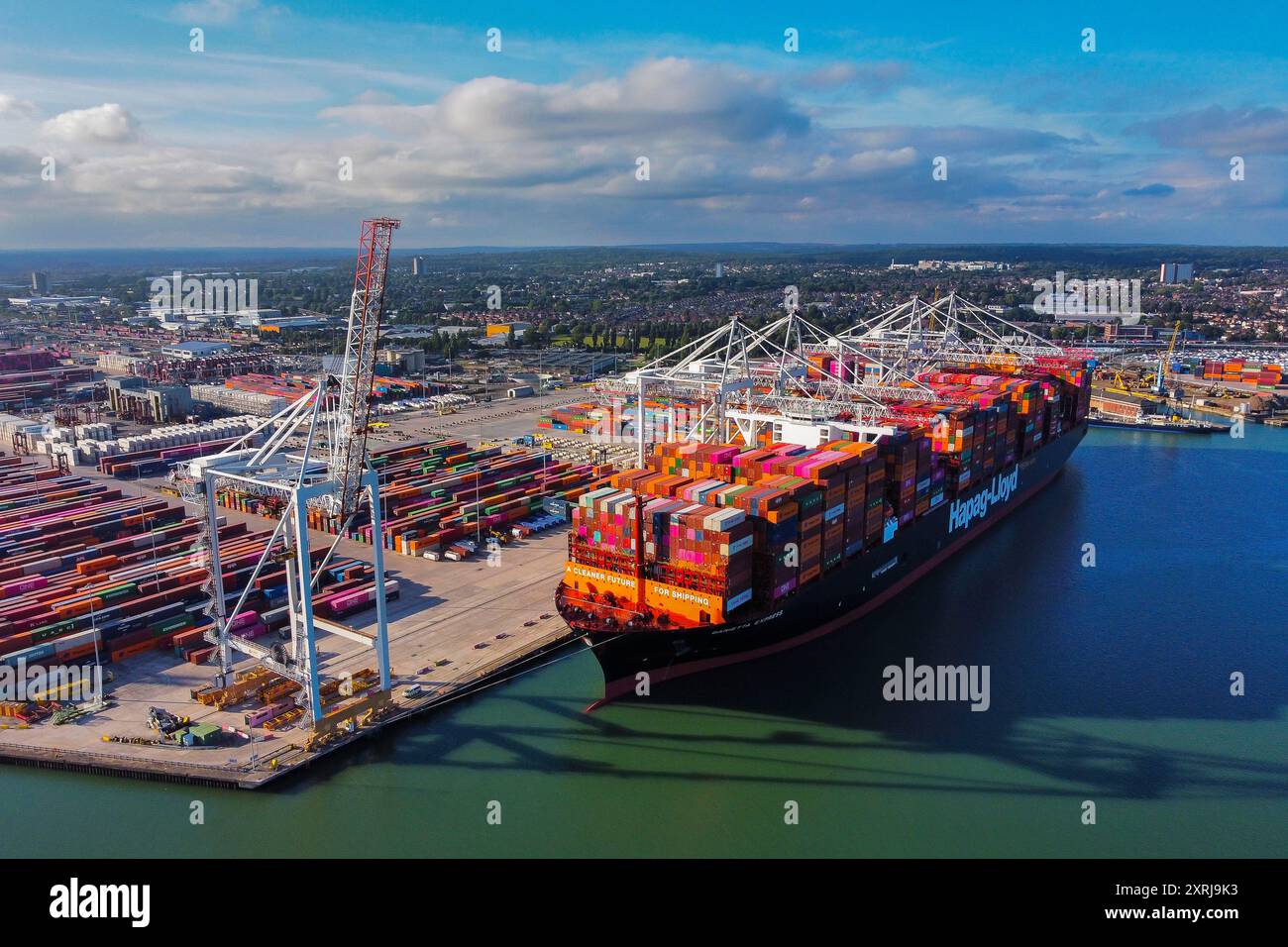 Southampton, Hampshire, Royaume-Uni. 10 août 2024. Vue aérienne générale des Western Docks au port de Southampton dans le Hampshire avec le porte-conteneurs Hapag-Lloyd Damietta Express amarré qui porte le message « Un avenir plus propre pour le transport maritime ». Après le port de Felixstowe, Southampton est le deuxième plus grand terminal à conteneurs au Royaume-Uni, traitant un trafic de 1,5 millions d'équivalents vingt pieds (EVP). Crédit photo : Graham Hunt/Alamy Live News Banque D'Images