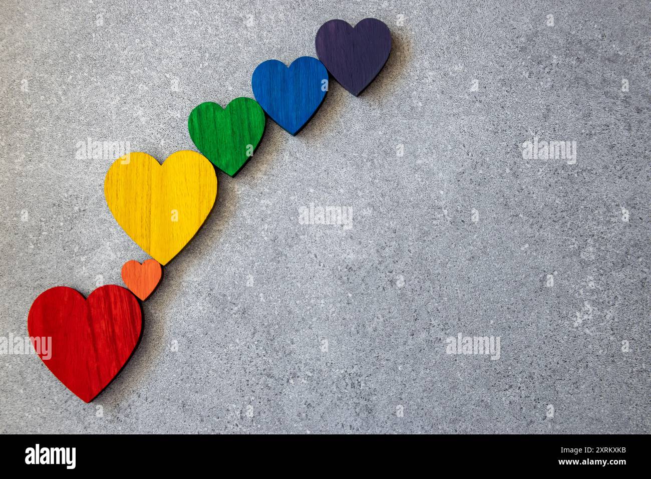 Rainbow couleurs coeurs en bois sur le fond noir de pierre. Drapeau LGBT. Banque D'Images