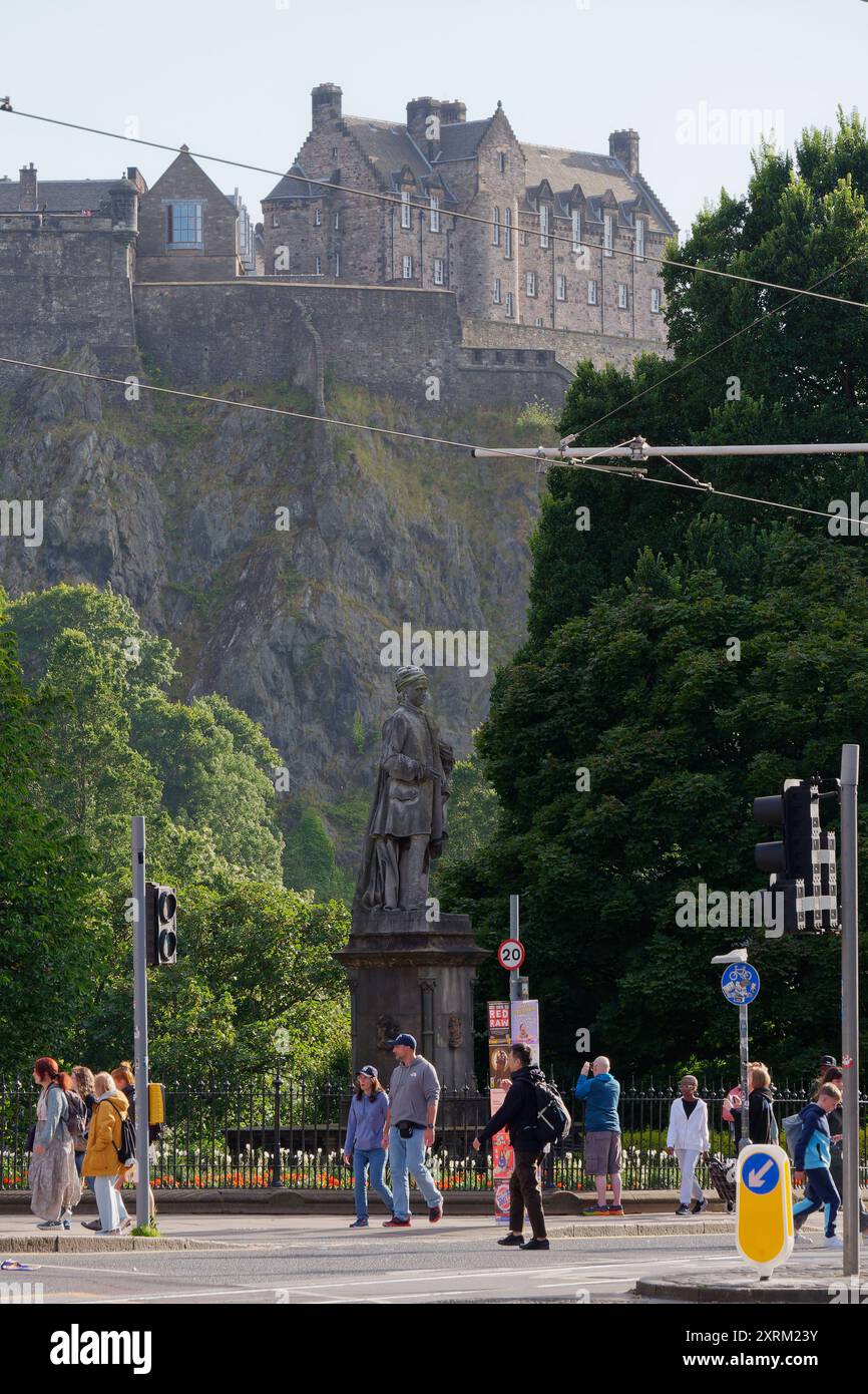Les gens passent devant une statue dans Princes Street Gardens avec le château d'Édimbourg derrière à Édimbourg, capitale de l'Écosse, le 10 août 2024 Banque D'Images